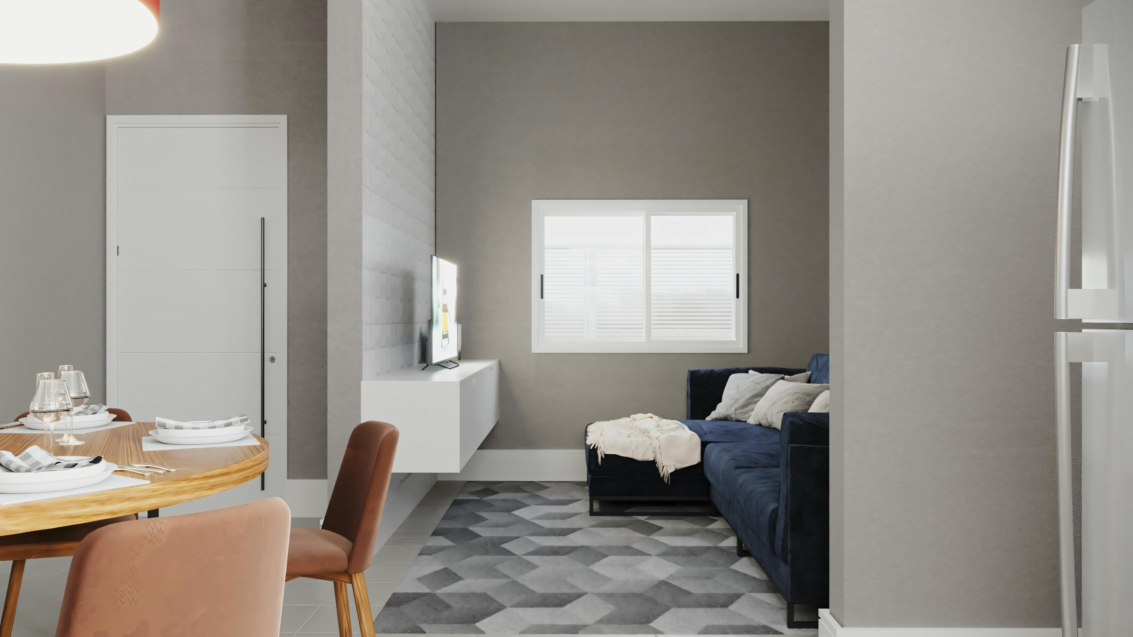 A living space with a dining table for two, an open kitchen area in the background, and an unmade bed visible through an open door.