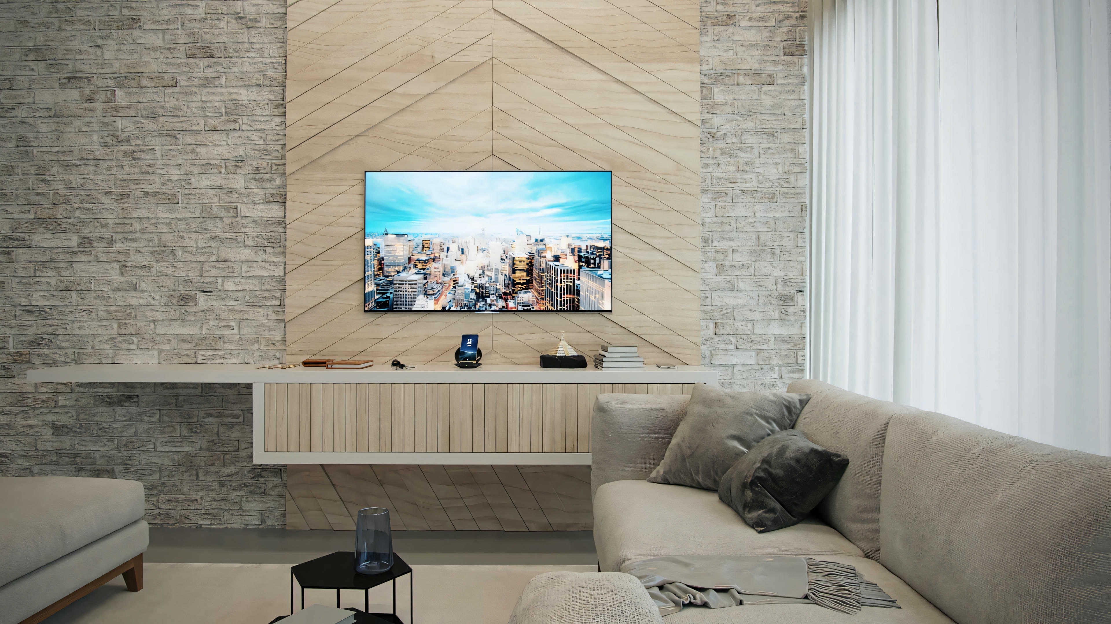 Una sala de estar con sofá grande, mesa de centro redonda y televisión montada en una pared de piedra.