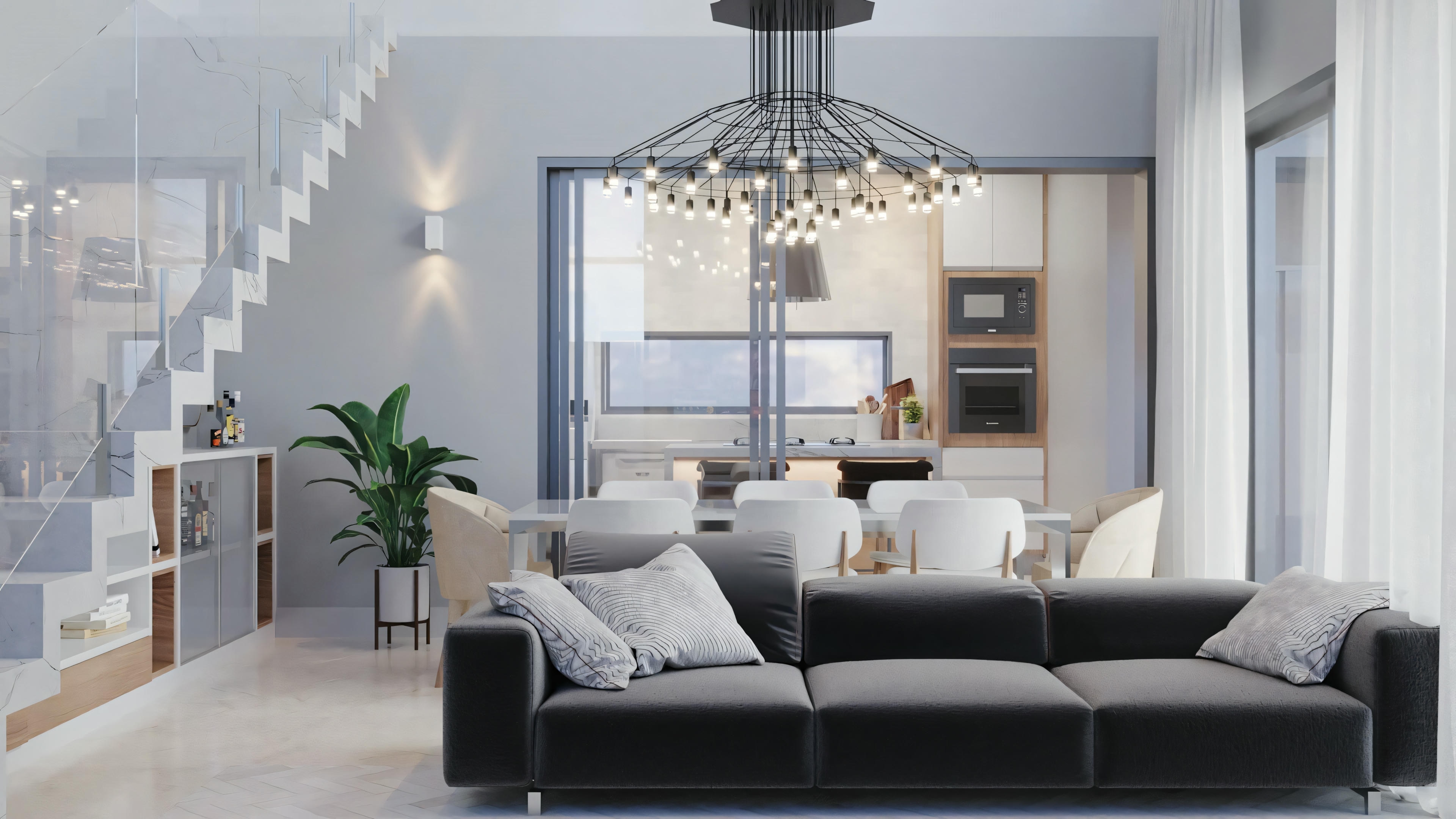 Uma sala de estar com sofá cinza, poltronas e um lustre elegante. Grandes janelas permitem a entrada de luz natural.