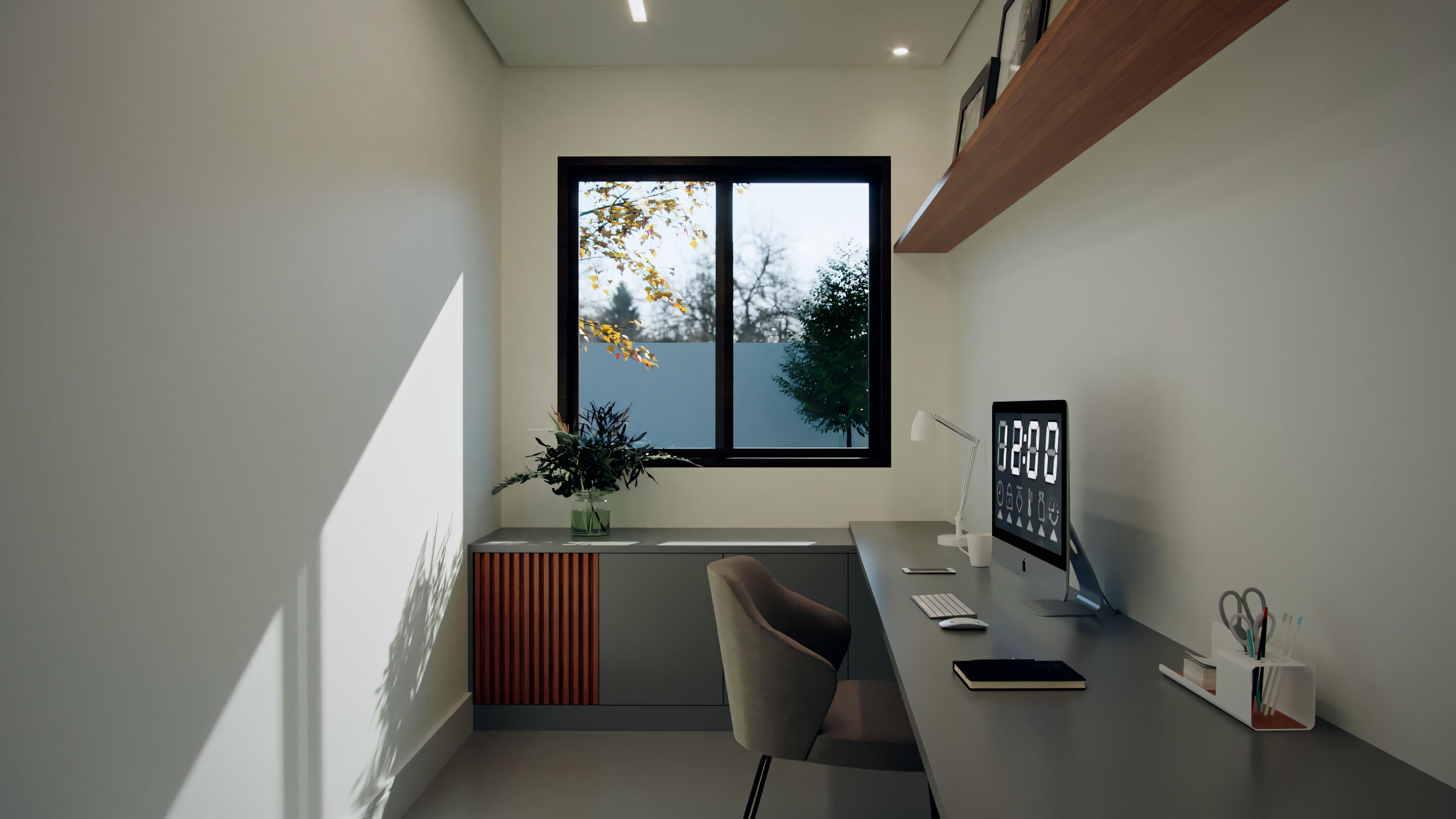 An interior space with a desk, computer, chair, and a window overlooking outside greenery. The room appears well-lit with natural light.