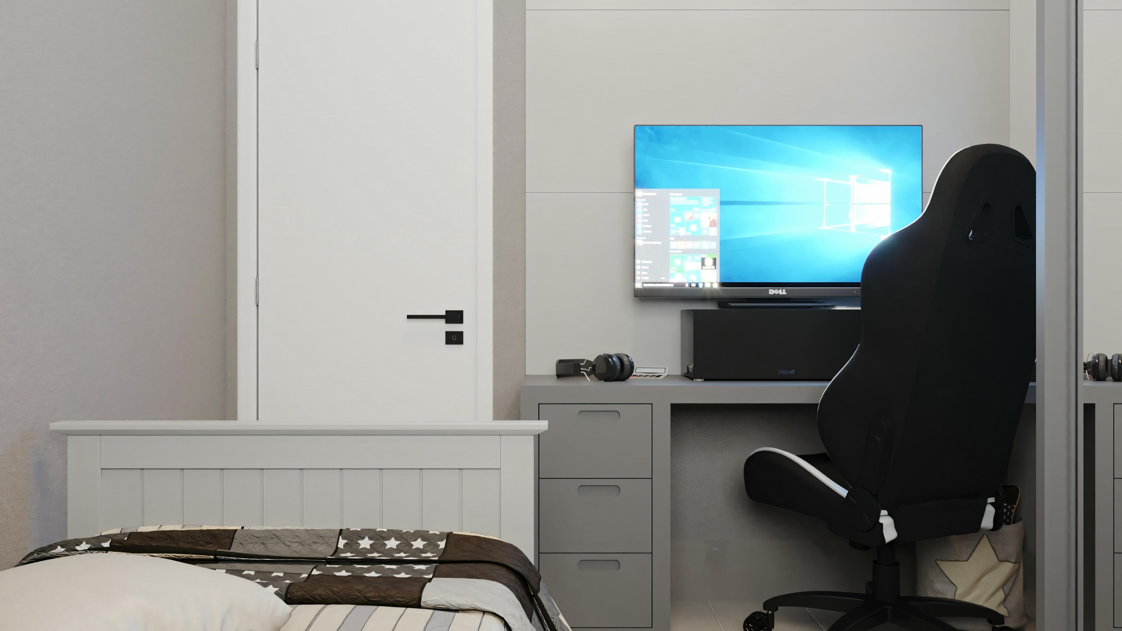 A workspace with a black office chair, a desk with a computer monitor displaying a blue screen, and a bed in the background.