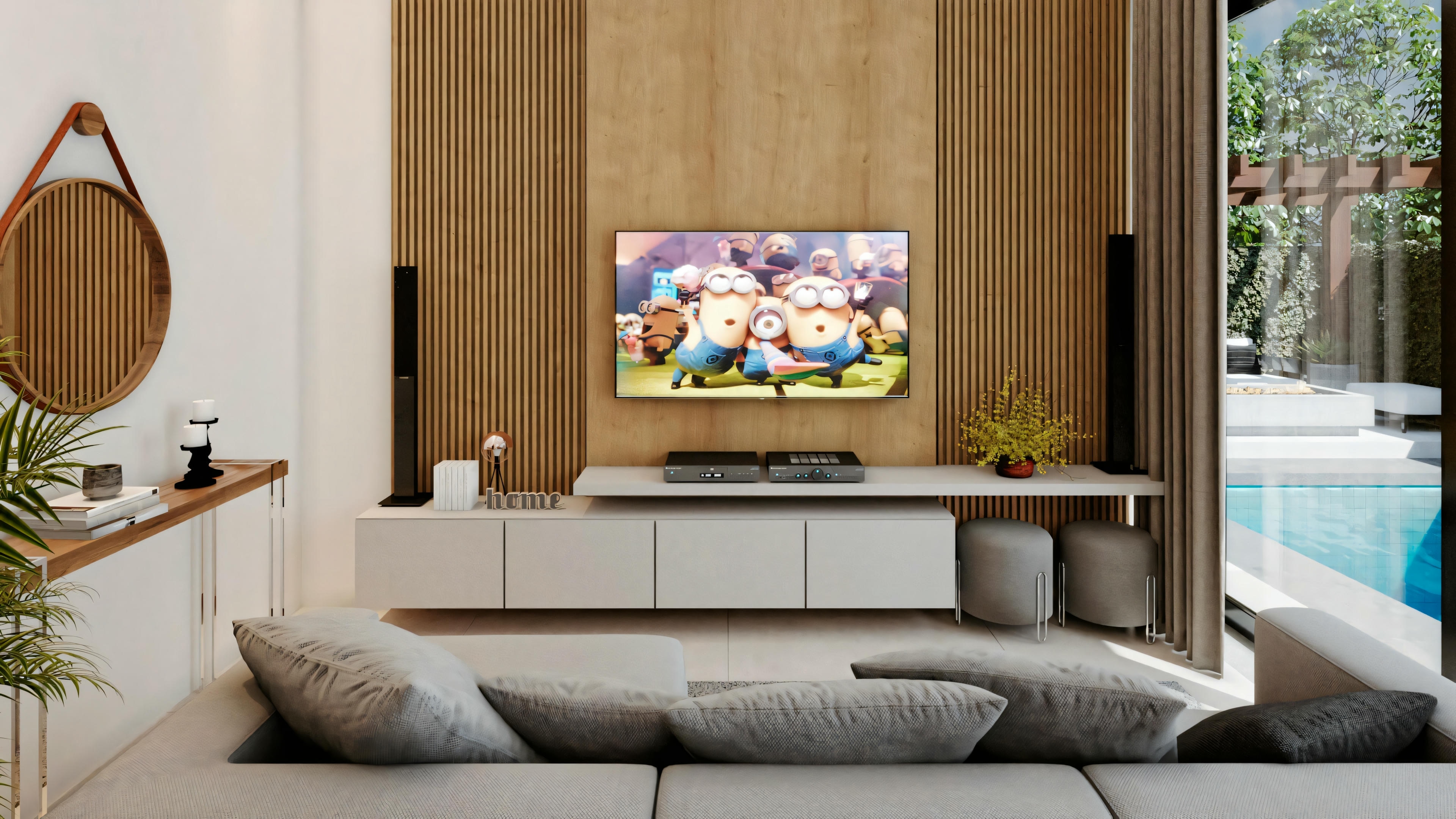 A modern living room with a large television screen on a wooden wall, a gray sofa, and decorative items such as a round mirror and plants.