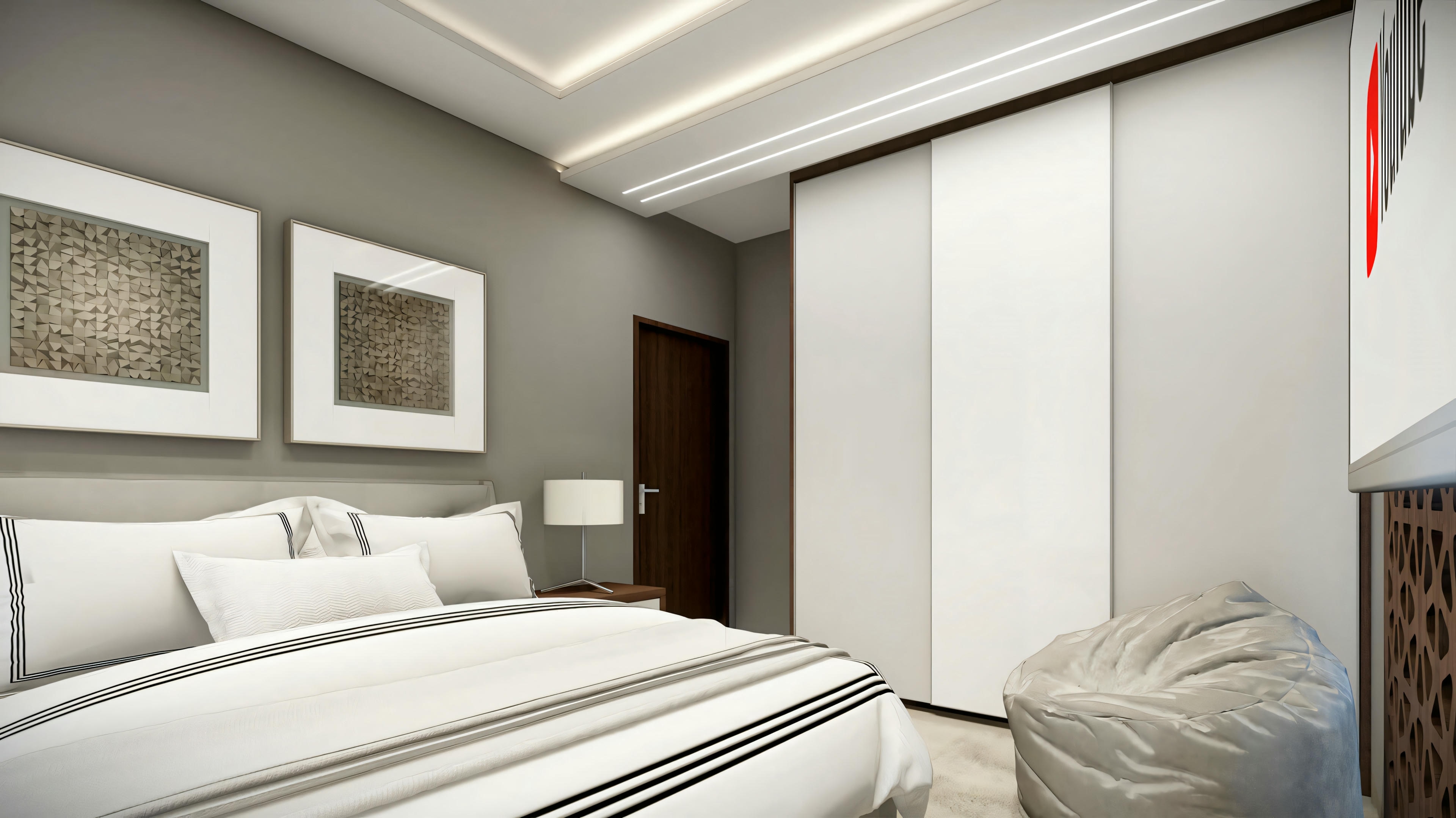 A bedroom with a large bed, white bedding, and pillows against a padded headboard. There is a side table with a lamp and a picture or mirror above it.