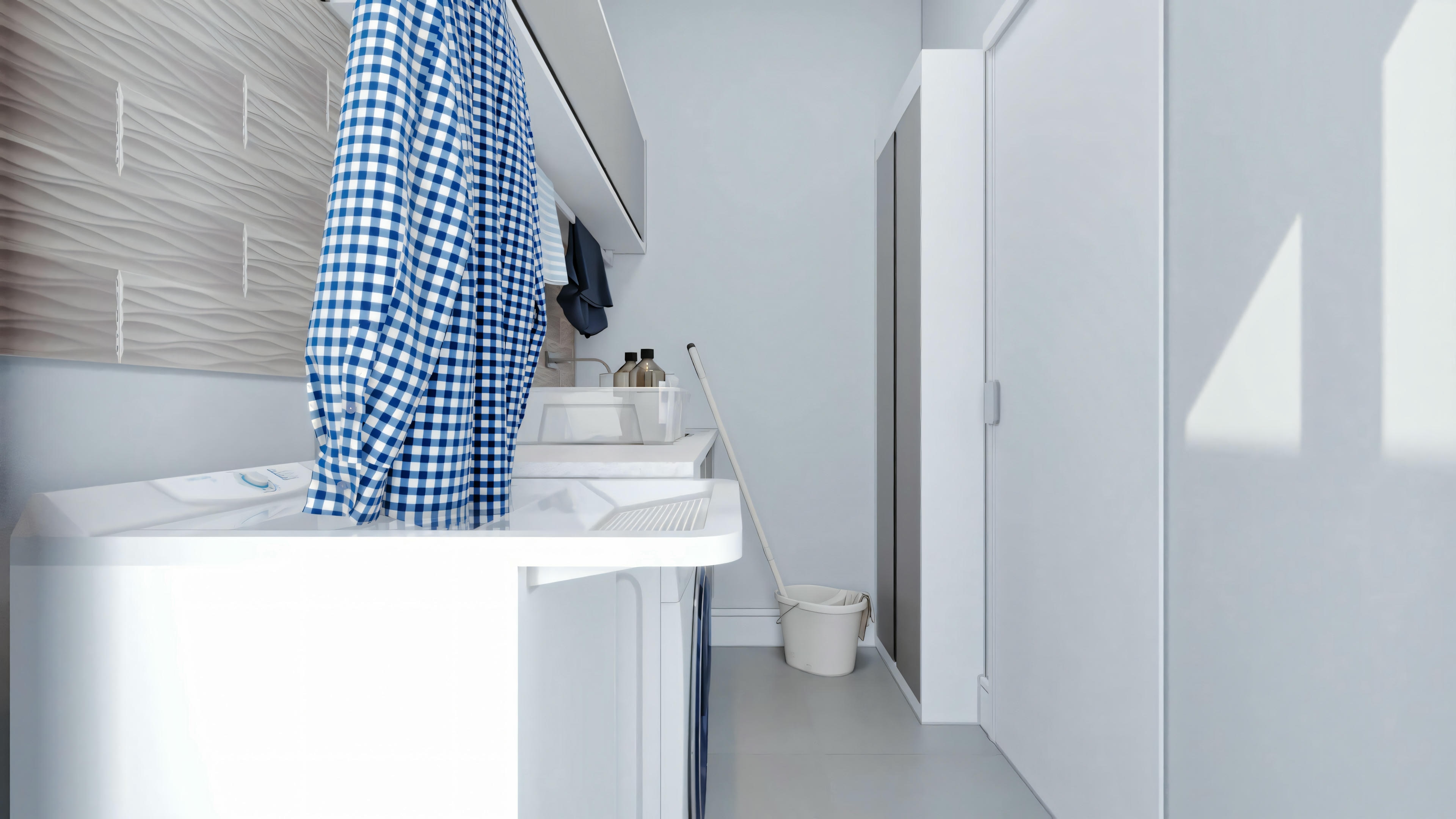 Una lavandería moderna con encimera blanca, armarios superiores blancos y pared parcialmente cubierta con azulejos azules.