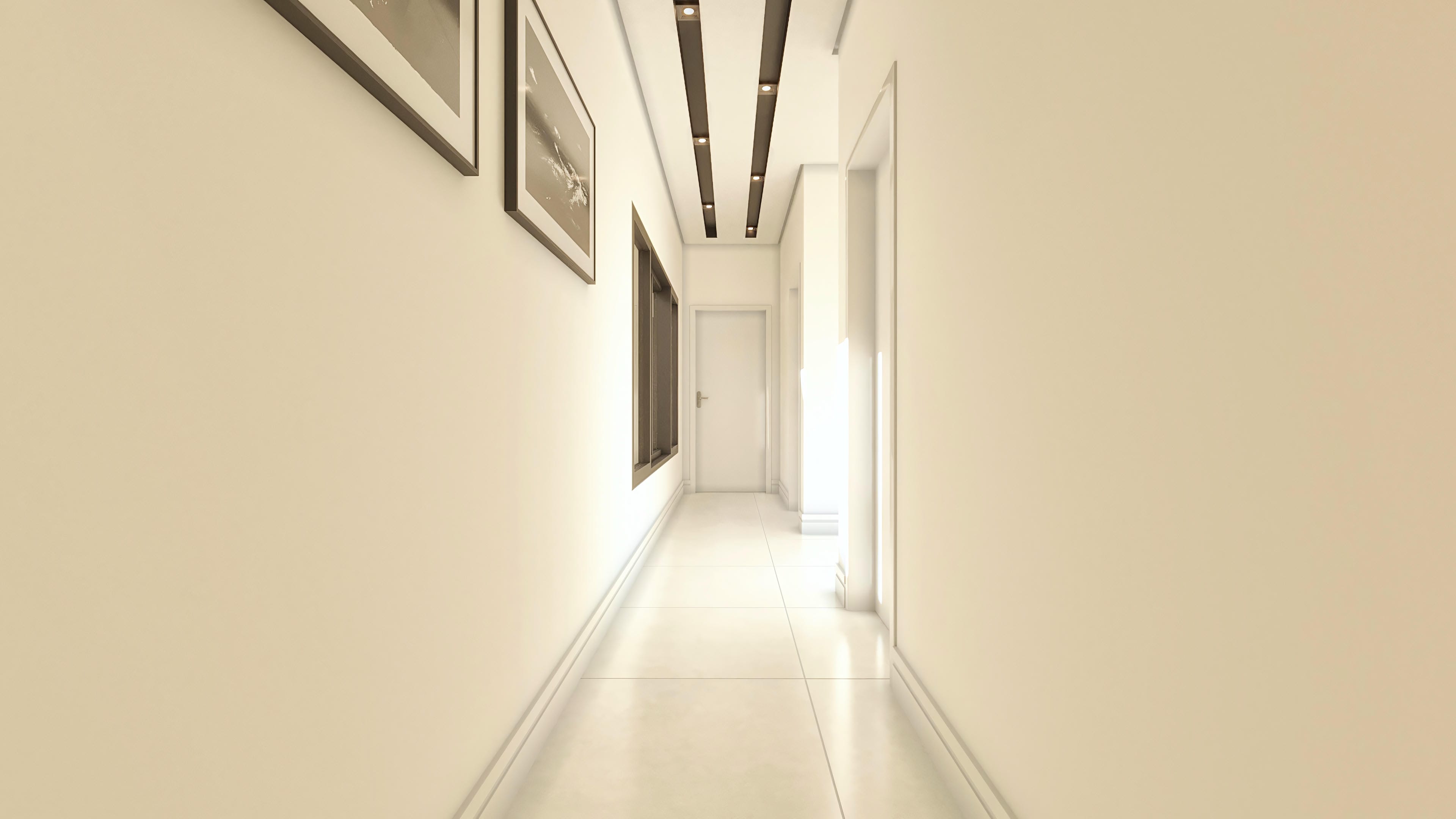 Corredor interno de casa moderna, com paredes em tom creme, piso de porcelanato claro e iluminação embutida no teto. Obras de arte emolduradas adornam a parede.