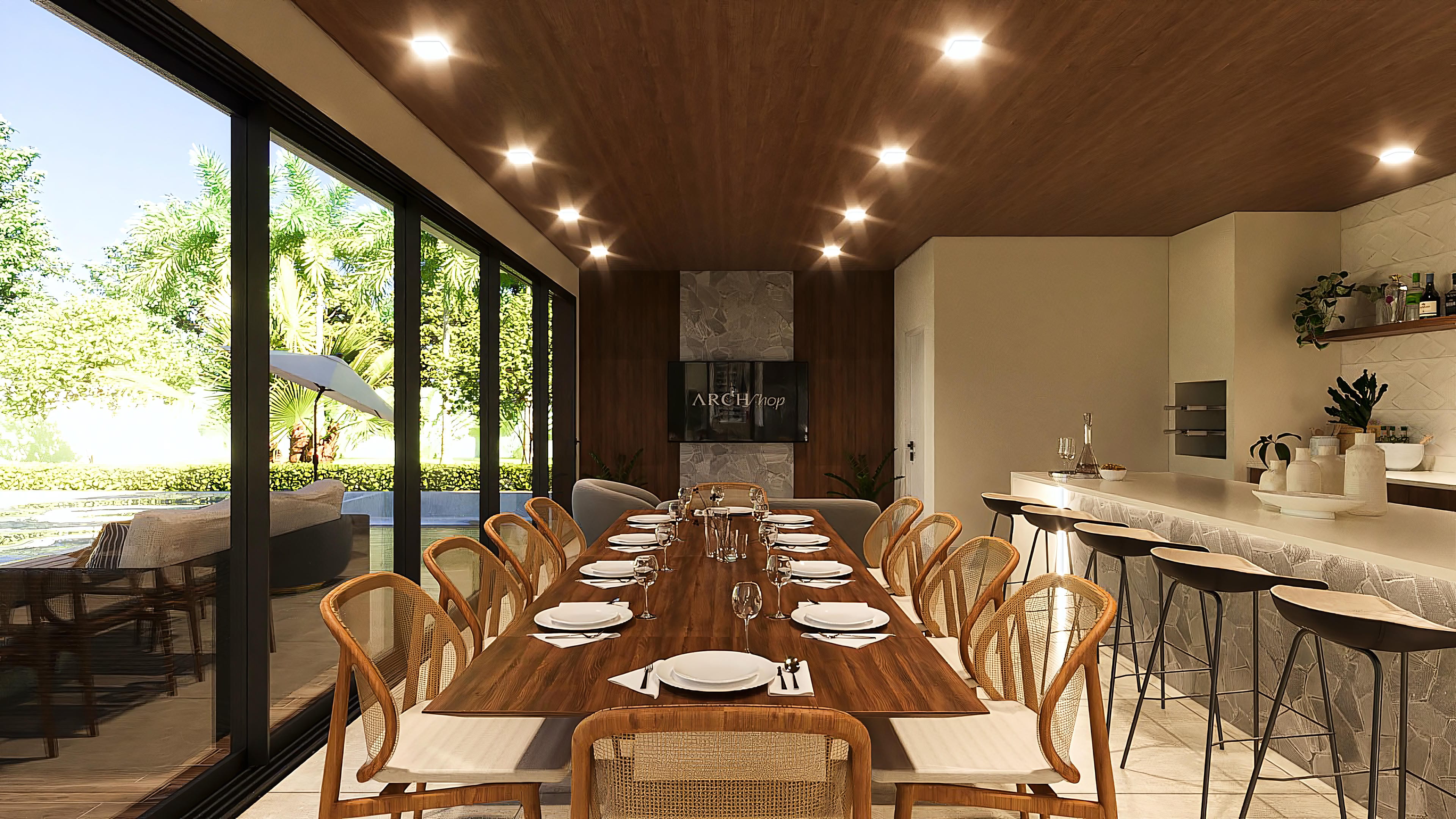 Interior de área gourmet lujosa con amplia mesa de comedor y barra con taburetes, integrada al área exterior con piscina y exuberante paisajismo.