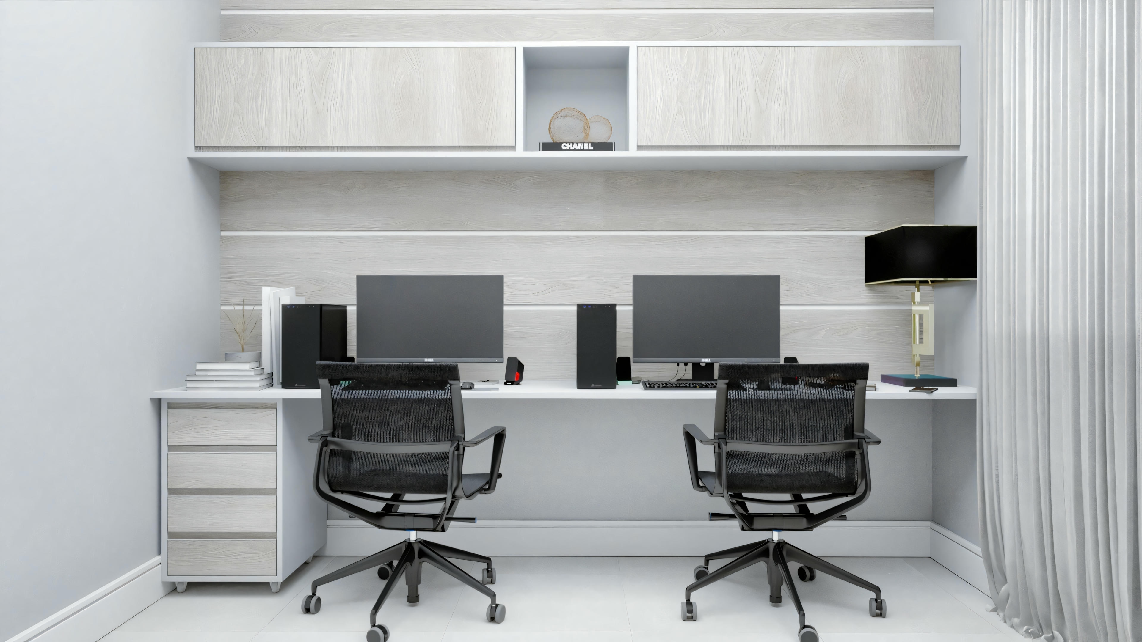 An office space featuring two black office chairs facing a desk with two computer monitors, set against a backdrop of white shelves filled with books and decorative items.
