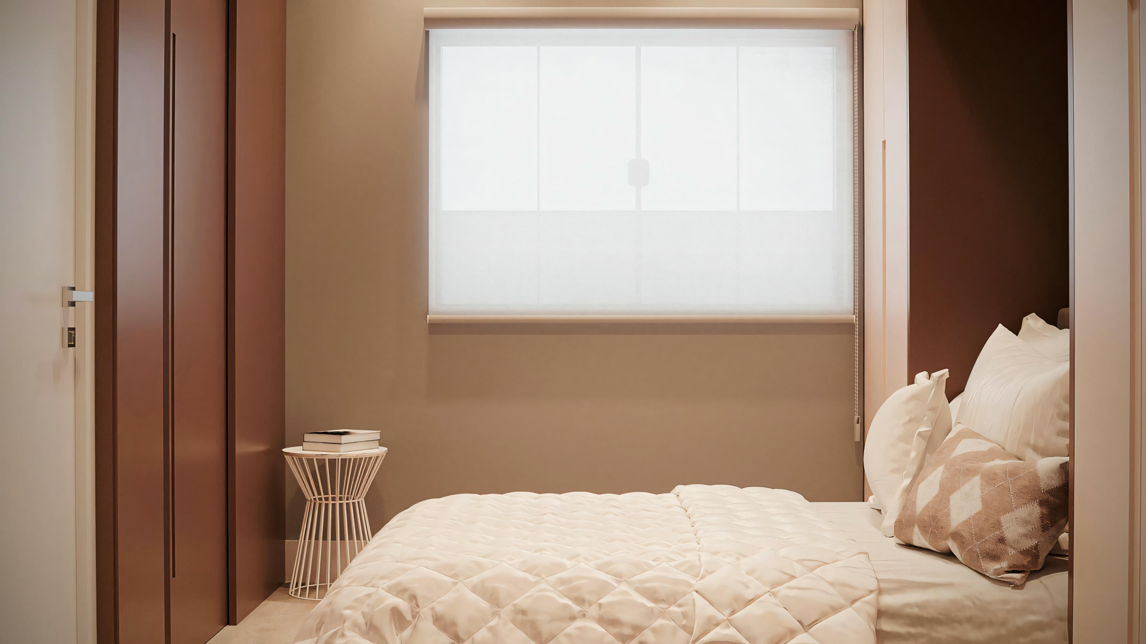 A bedroom with white bedding and a pillow, placed against a wall near a window with closed blinds.