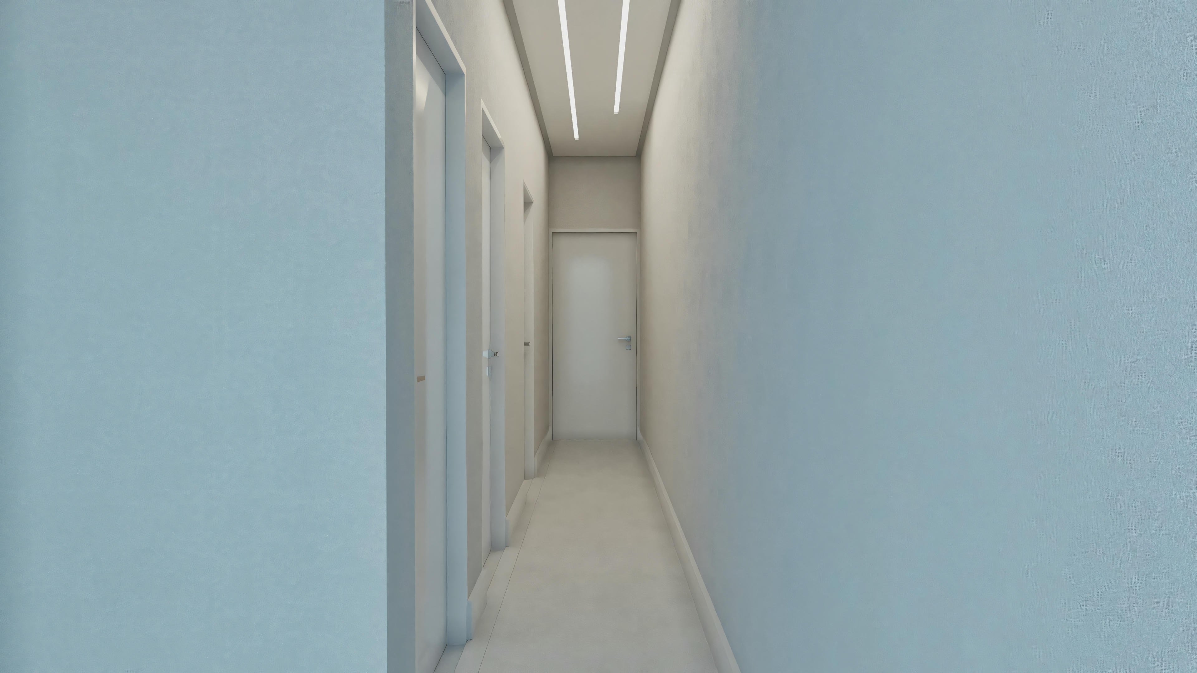 An interior hallway with light-colored walls, leading to a closed door at the end.