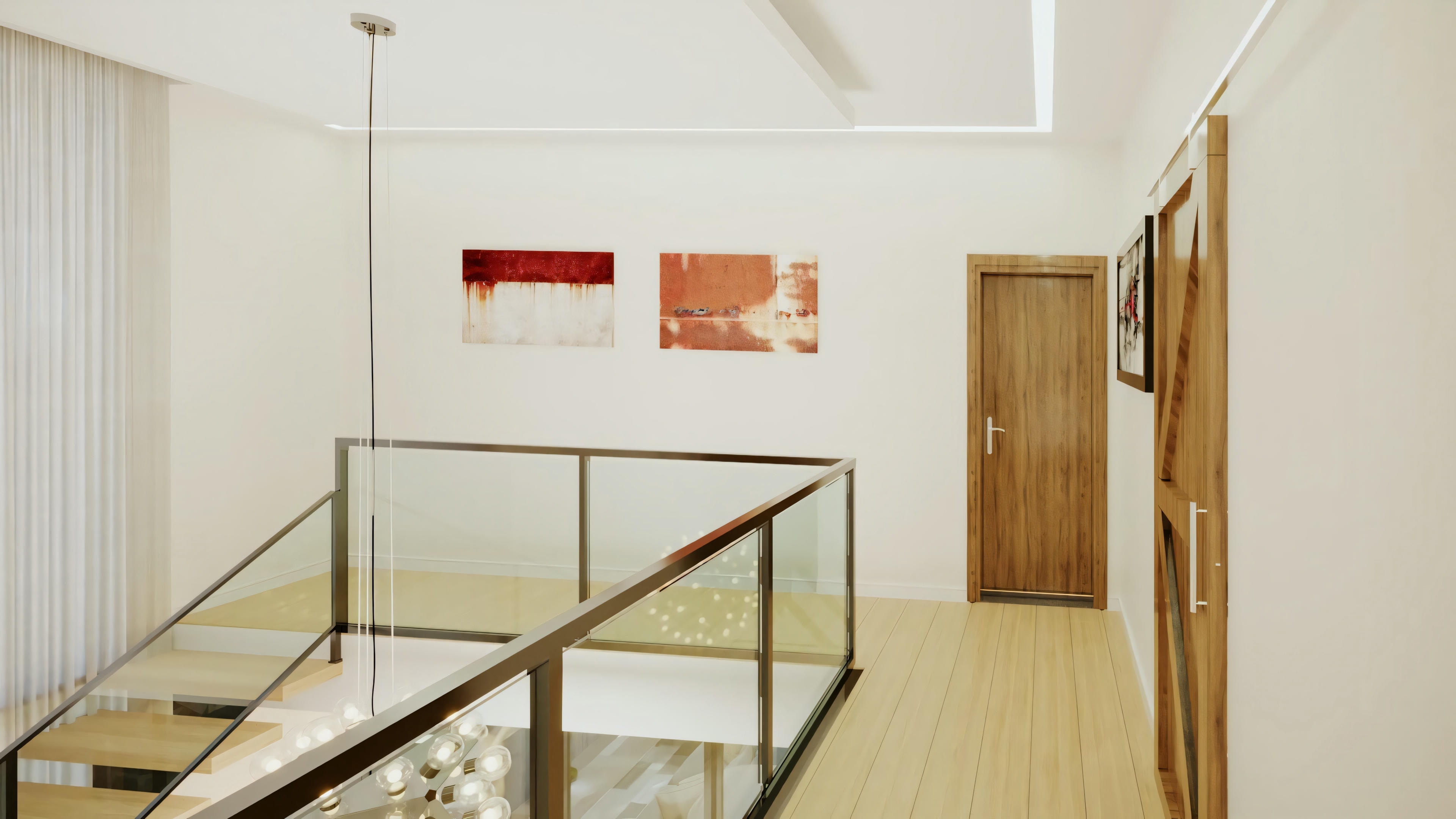 Una zona con barandilla de cristal, suelos de madera y paredes blancas decoradas con tres cuadros en tonos rojos.