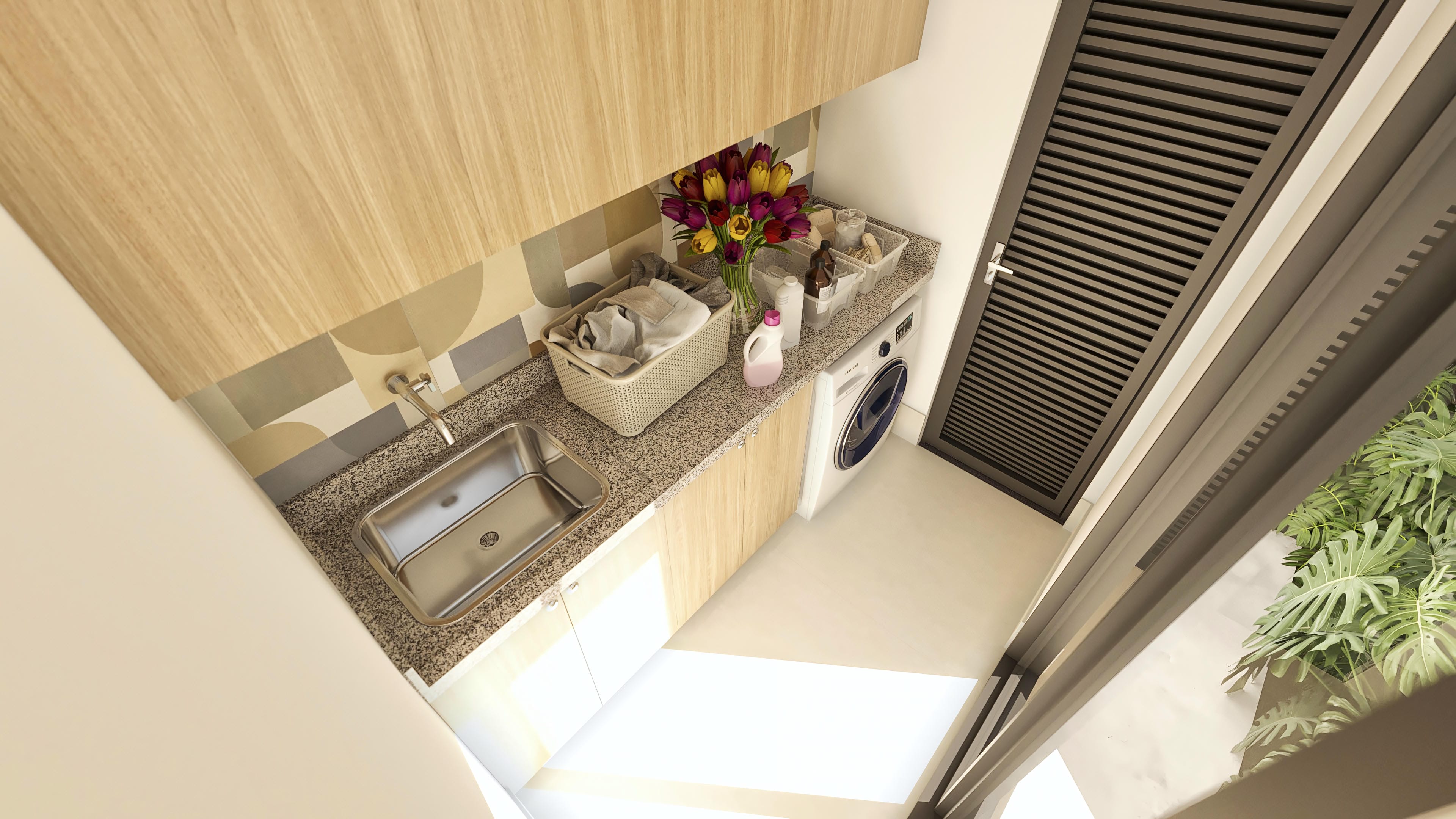 Interior of a compact and modern laundry room with wood-toned cabinets, granite countertop, stainless steel sink, and washing machine. Natural lighting enhances space functionality, with geometric tile details and a shuttered door.