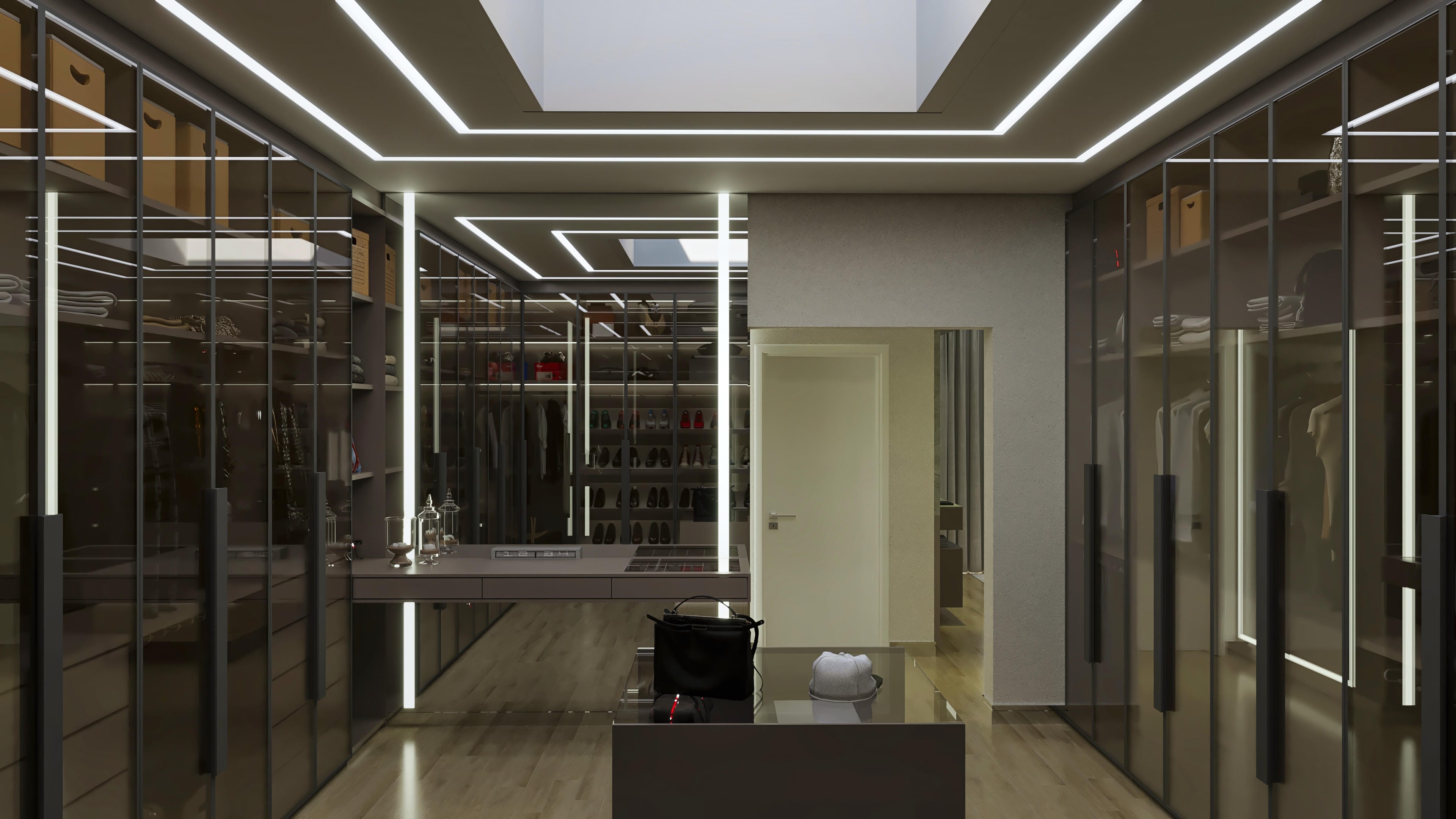 Interior de um closet moderno com armários altos e portas de vidro espelhado, iluminação LED embutida no teto e prateleiras organizadas. Uma ilha central com gavetas oferece espaço de armazenamento adicional.