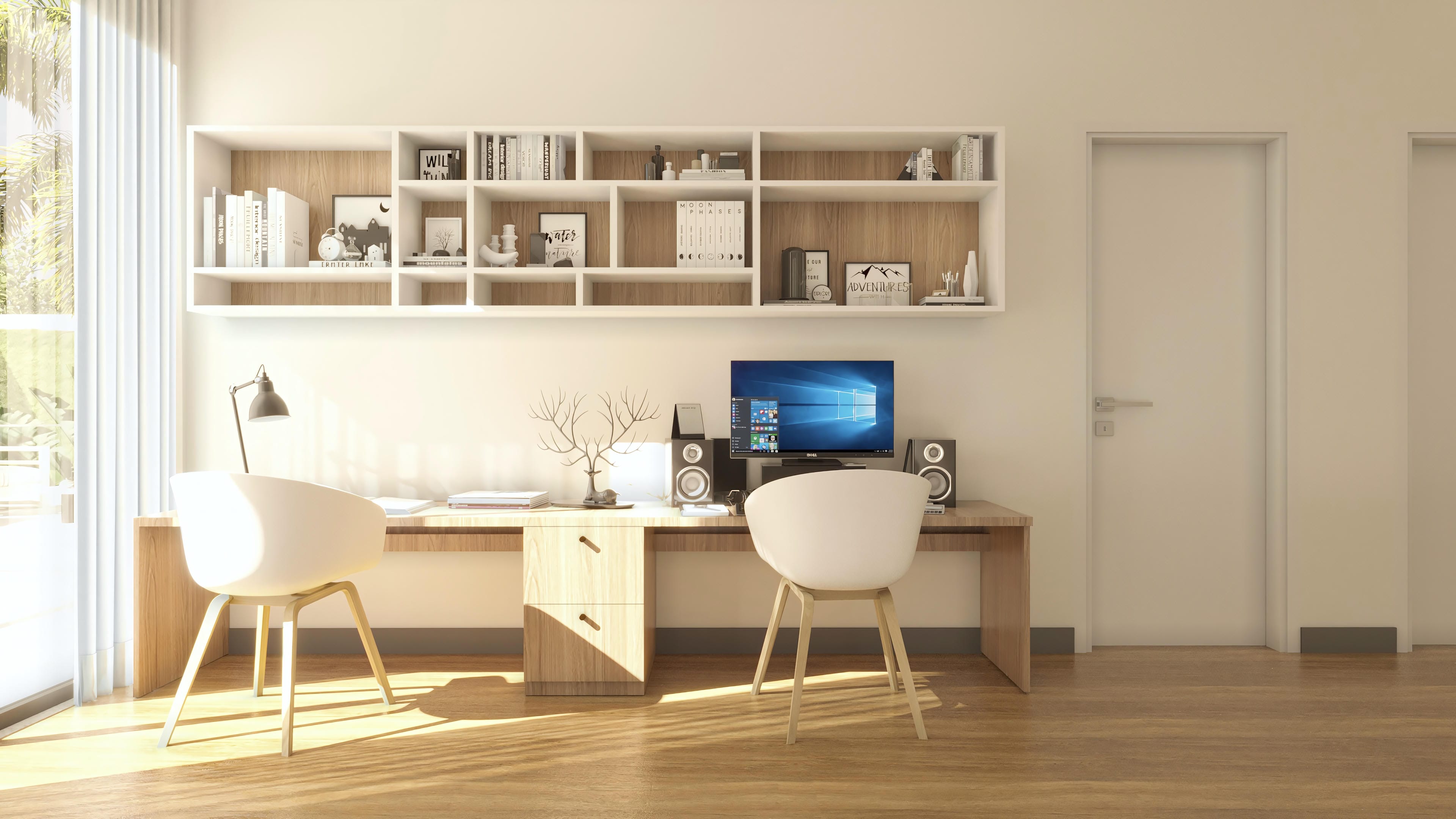 Ambiente de oficina moderno con escritorio de madera clara, sillas blancas, estantes superiores con libros y objetos decorativos, y puertas blancas.