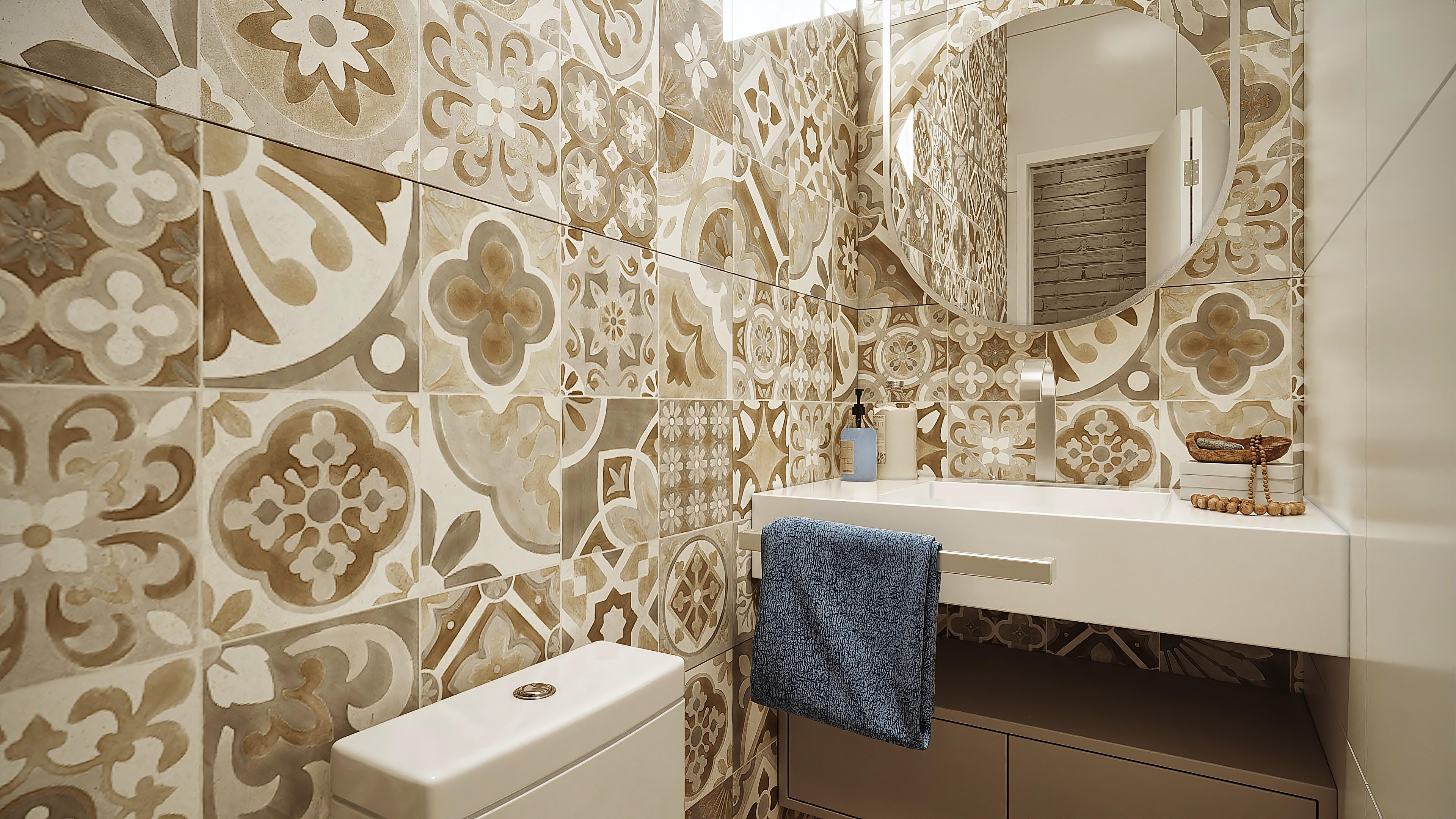 Detalle de baño con paredes revestidas en azulejos decorados en tonos beige y marrón, con lavabo blanco minimalista y espejo redondo.