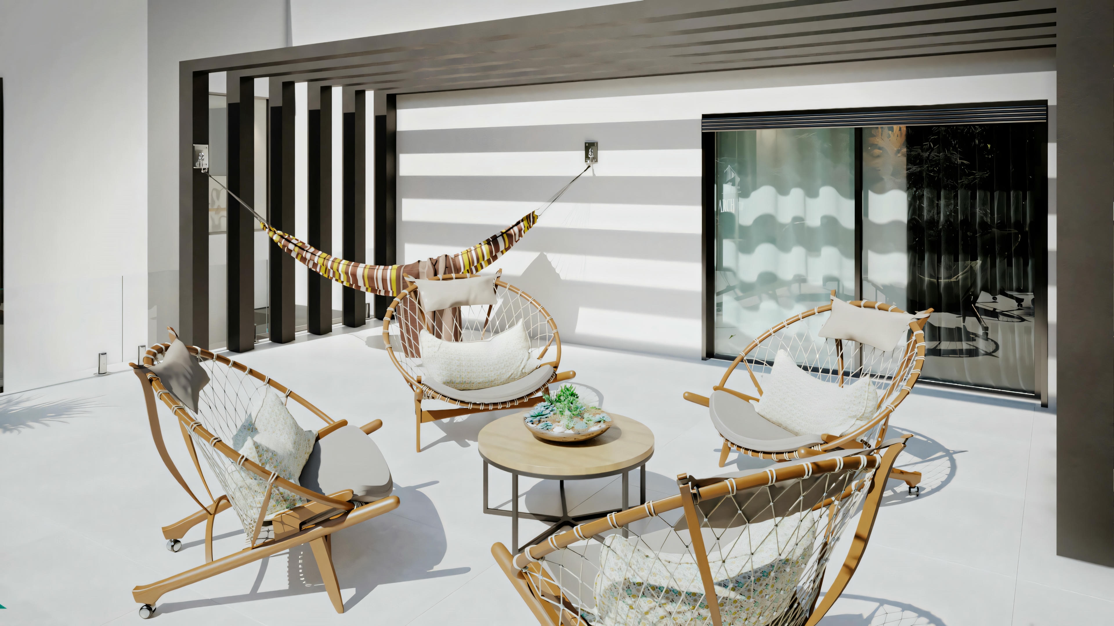 Zona de patio al aire libre con dos sillas mecedoras, una mesita con superficie de cristal y una puerta corredera abierta al interior de la casa.