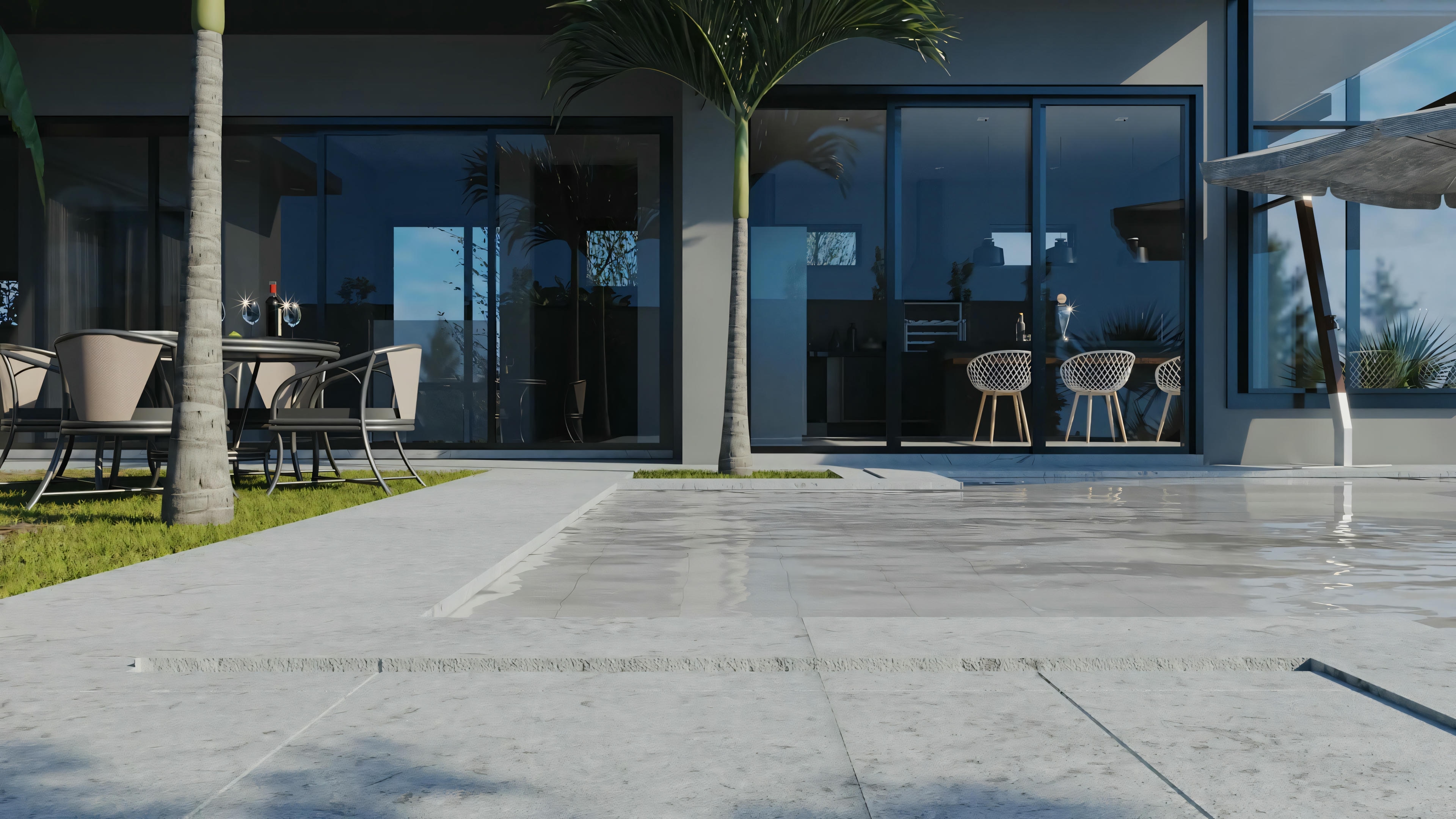 A modern outdoor patio with furniture, including chairs and a table, set on a paved area with a well-maintained lawn in the background.