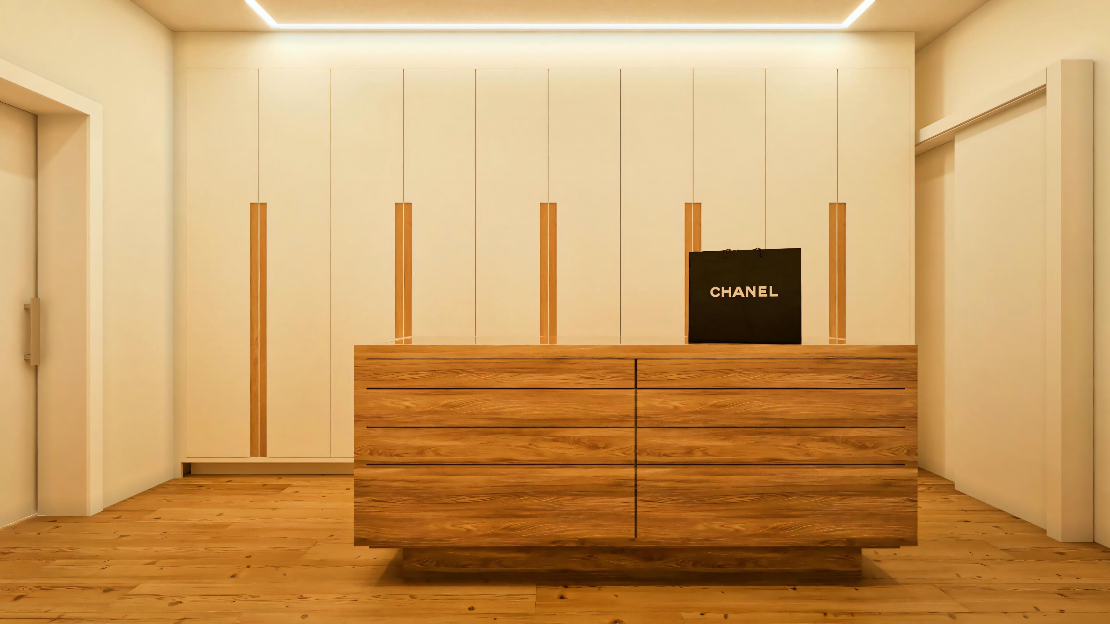 Detalhe do closet da suíte no projeto arquitetônico do sobrado de 330m², com foco na ilha central em madeira natural com múltiplos gaveteiros. Ao fundo, armários planejados com portas claras e puxadores verticais em madeira. Piso de madeira e iluminação de teto visíveis.