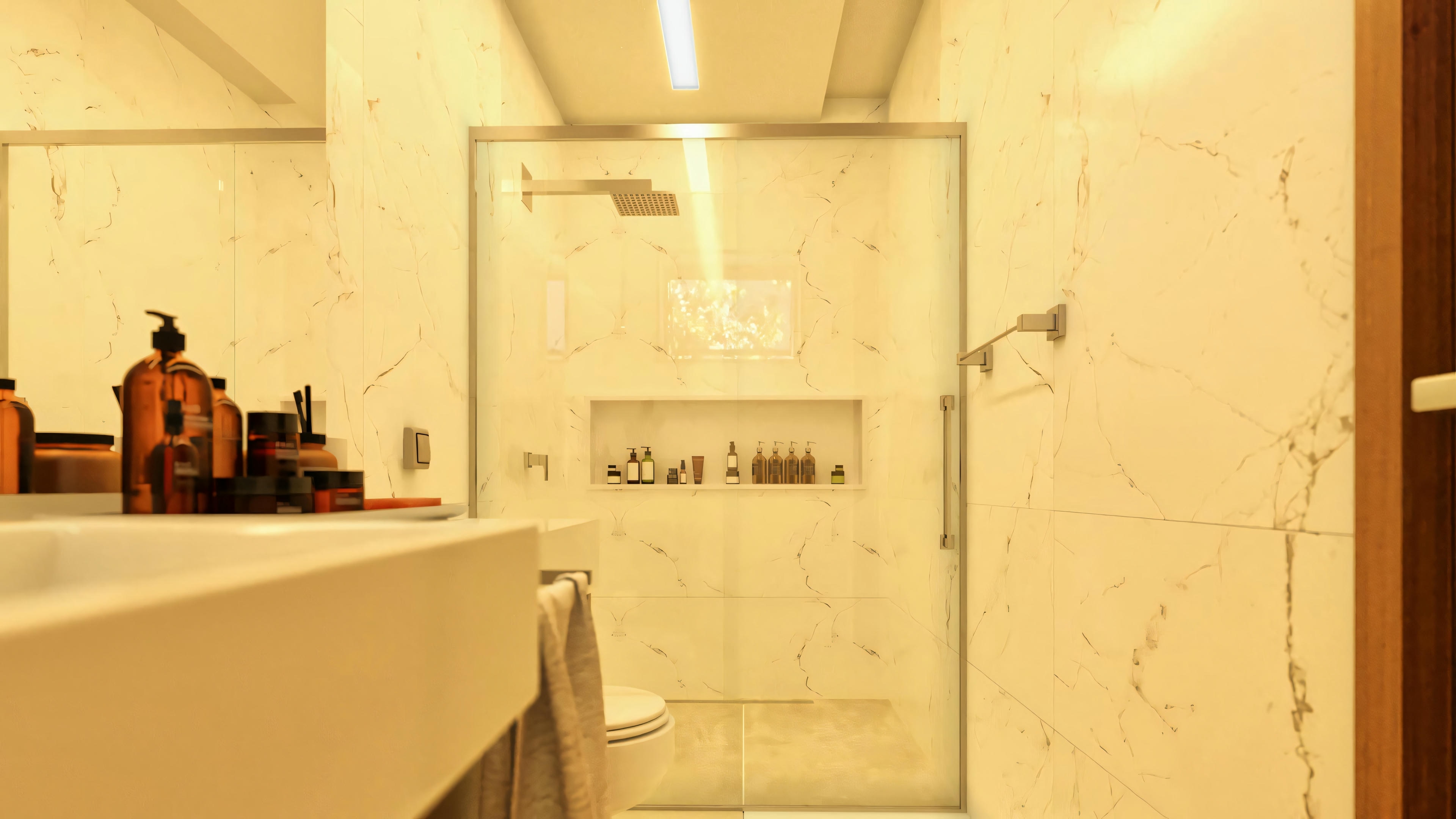 Primer plano de la ducha en baño de suite de proyecto de casa moderna, destacando el nicho empotrado, el revestimiento en porcelanato marmolado, la grifería tipo 'lluvia' y la iluminación en el cielorraso. Casa posee 4 suites, 7 baños, oficina, área gourmet y piscina en terreno 20x35.