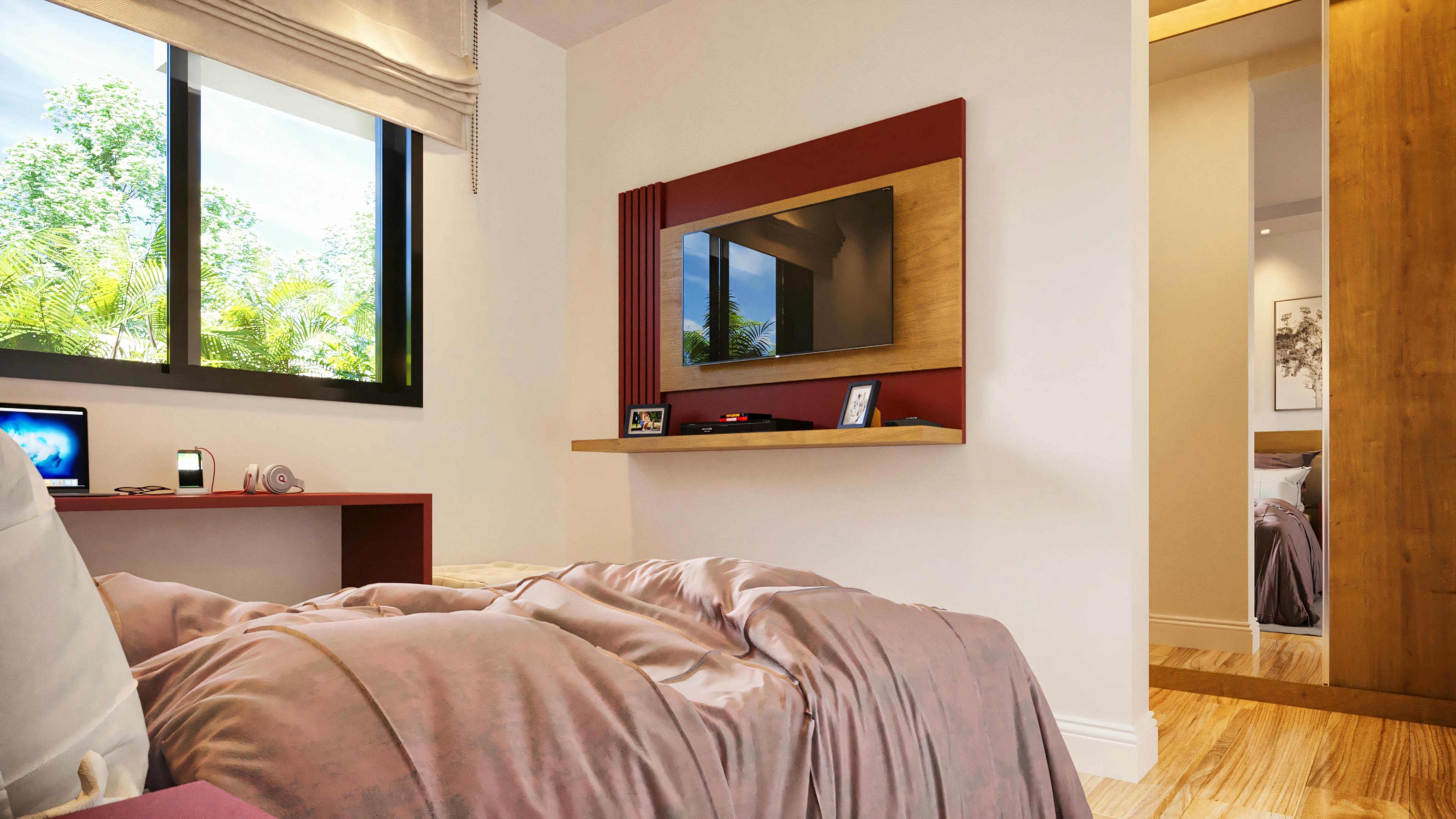 Quarto de suíte com cama, painel de TV vermelho e madeira, bancada de estudos junto à janela e porta de armário espelhada refletindo o ambiente.