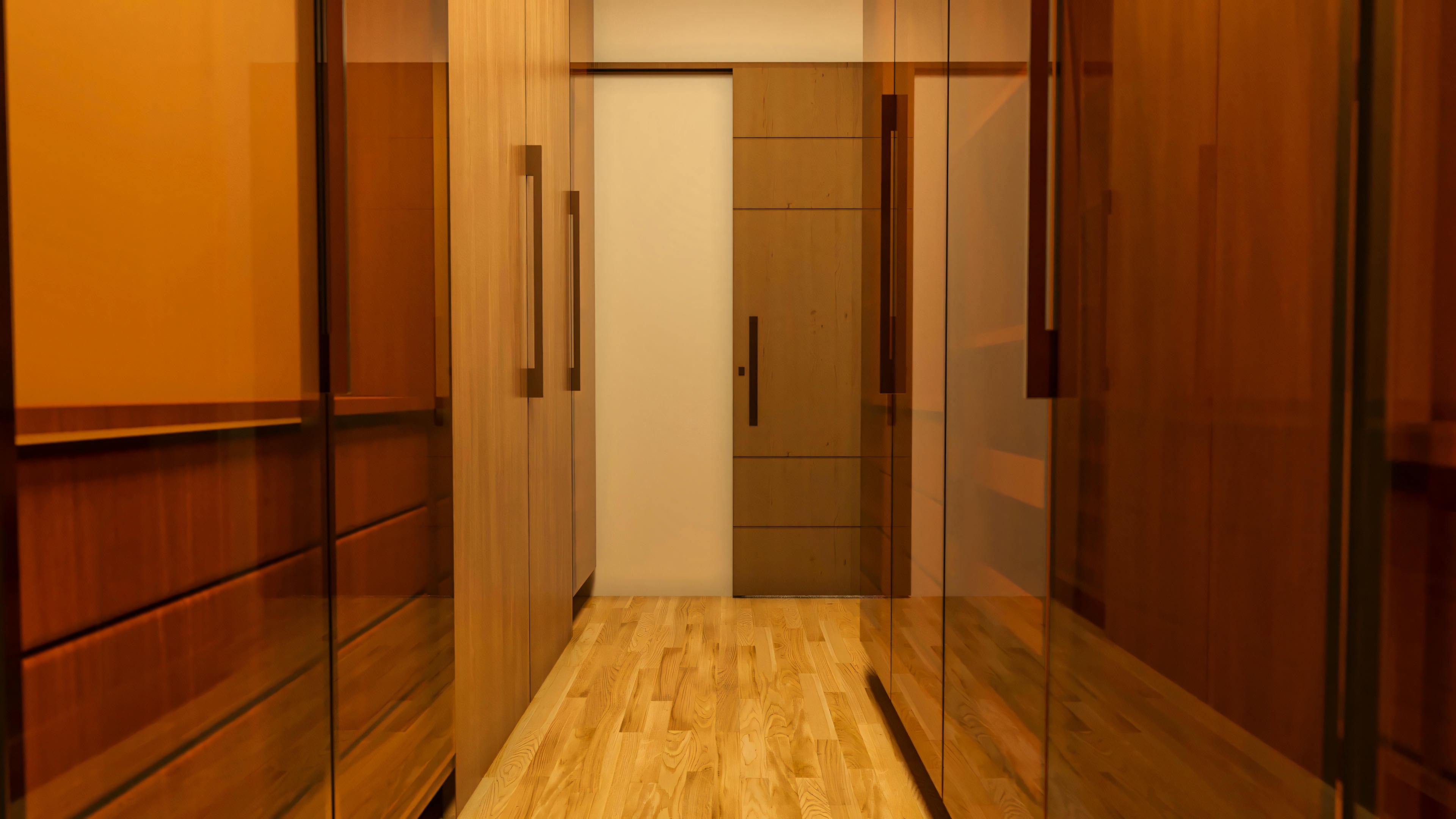 Vista interna del closet con armarios de madera y puertas reflectantes, perteneciente a una suite del proyecto de casa con 4 habitaciones, piscina y quincho. Este modelo de casa en terreno de 20x25 ofrece 394.84m² de área construida, incluyendo oficina.