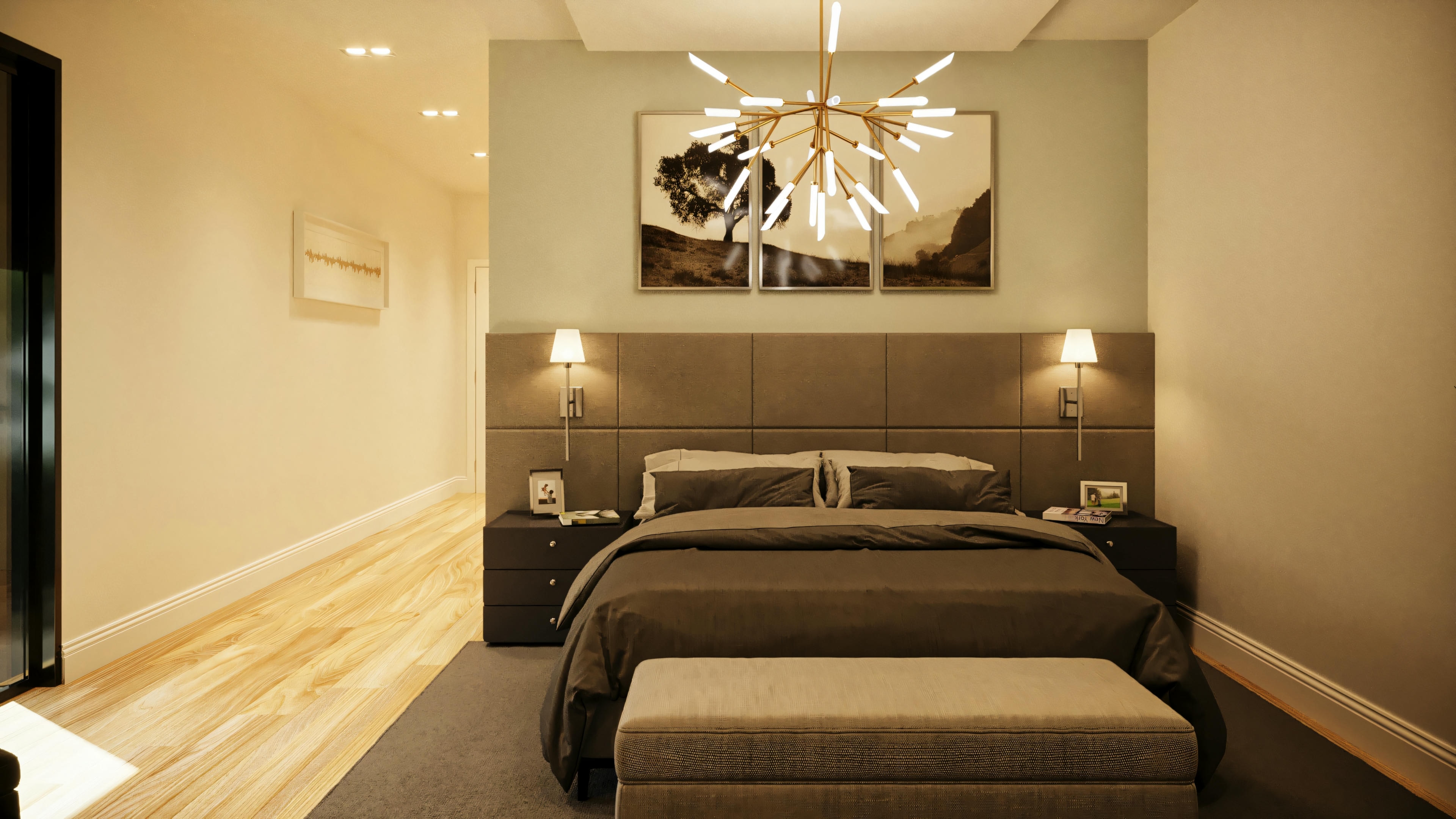 Vista do corredor de acesso à cama da suíte master em casa térrea com 3 suítes, mostrando piso de madeira, cama com cabeceira estofada, iluminação com lustre e arandelas.