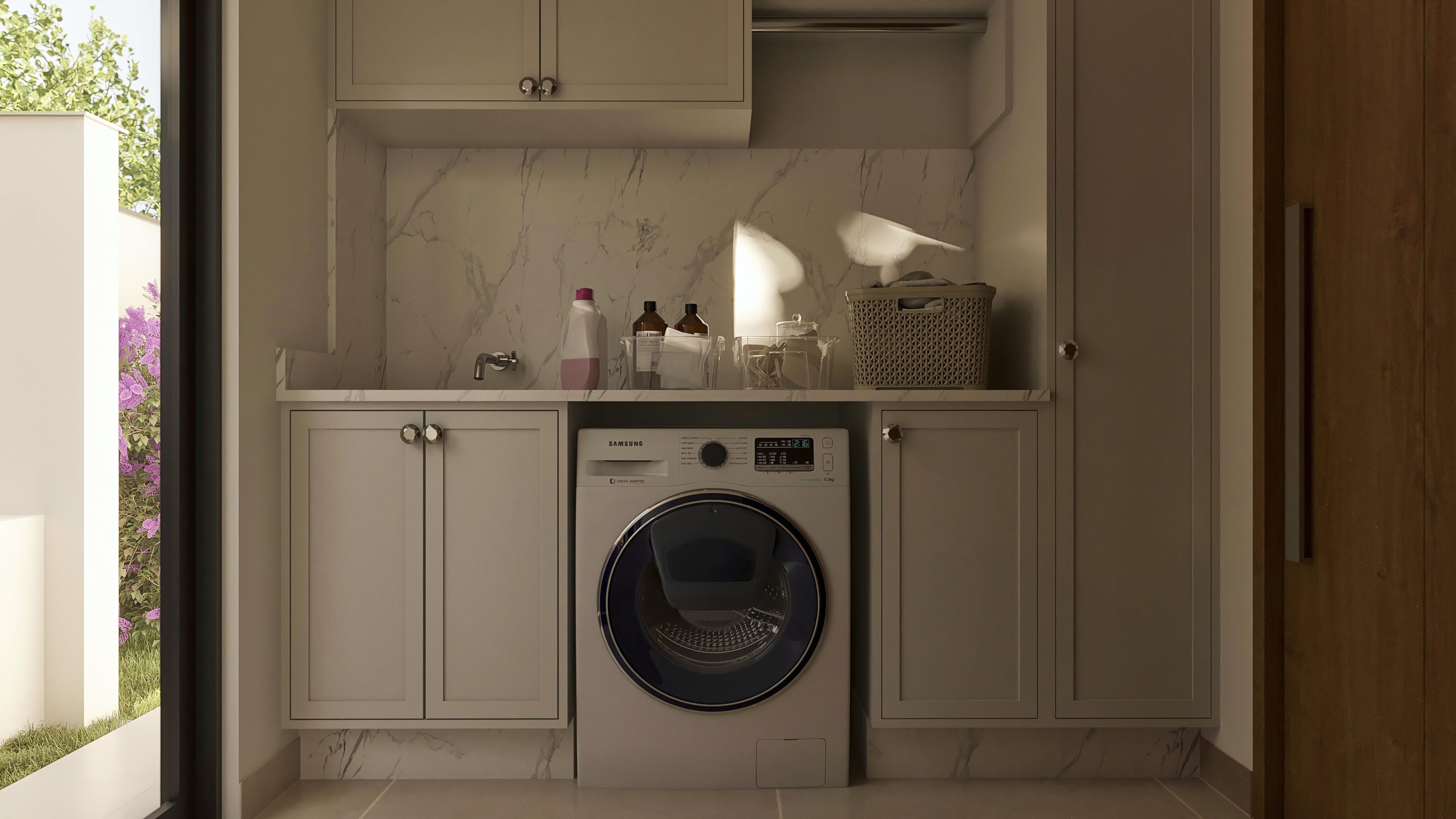 Laundry environment with Samsung washing machine, light-toned custom cabinets, and marble cladding. Functional and elegant space with access to the outdoor area with vegetation.