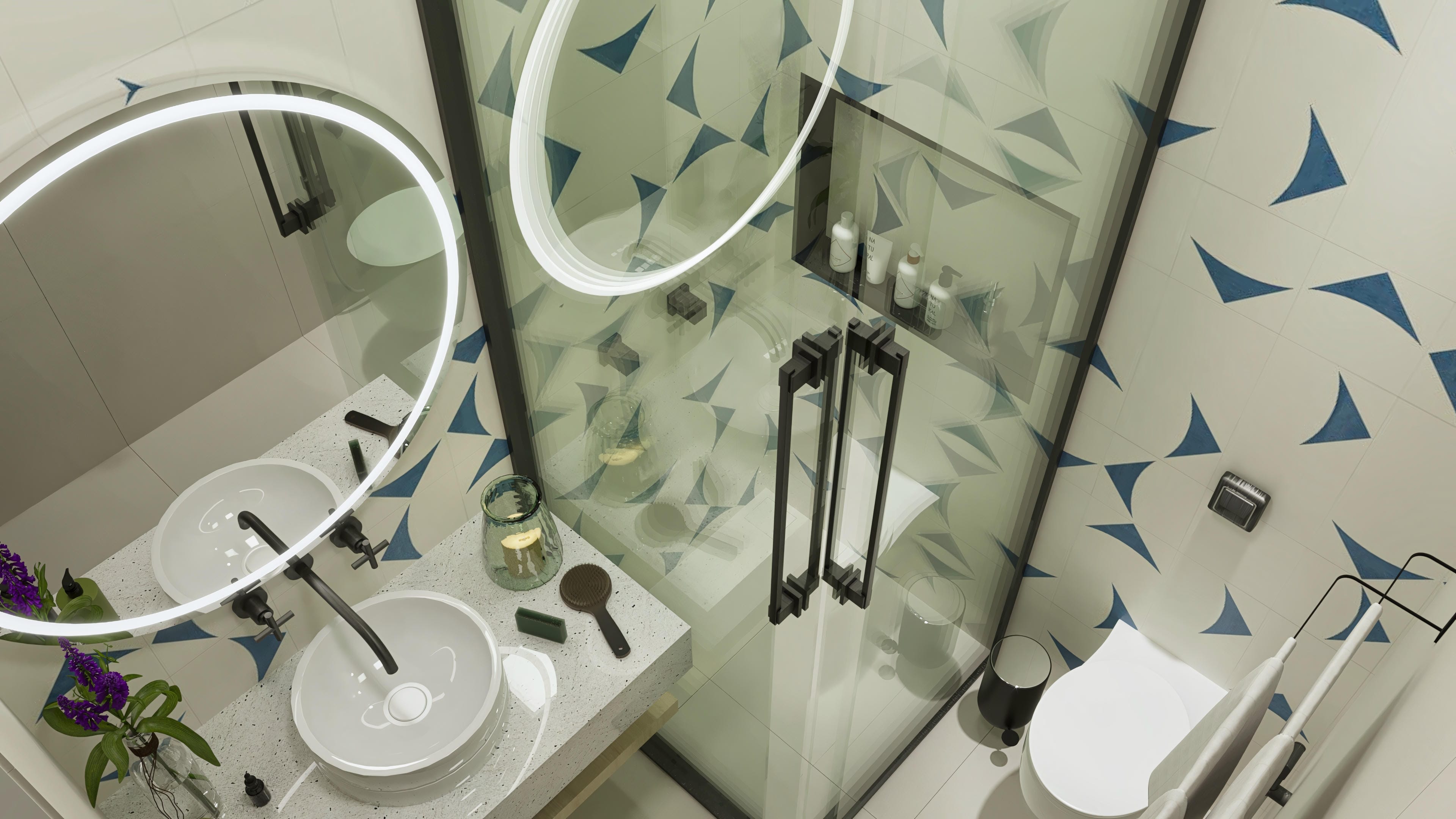 Interior of a modern bathroom with terrazzo countertop and vessel sinks, round mirror with LED lighting, and shower enclosure with geometric tiles in green and blue tones.