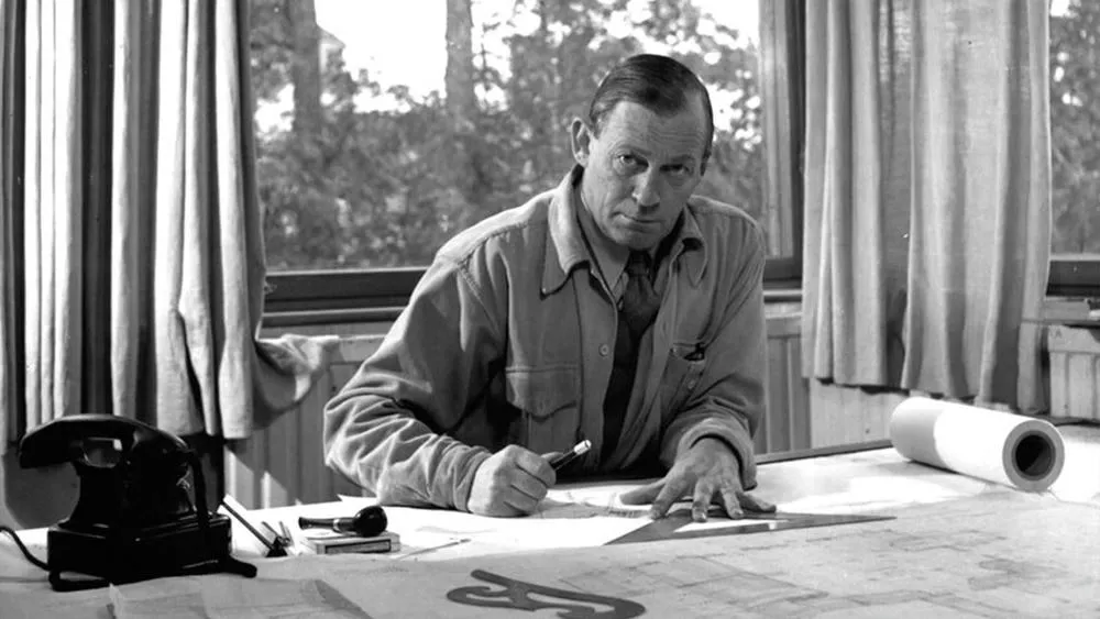 Retrato em preto e branco de Alvar Aalto, arquiteto famoso, trabalhando em uma prancheta.