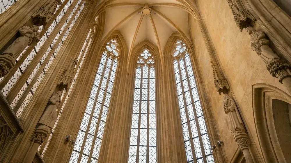Janelas góticas muito altas com vitrais coloridos, permitindo grande entrada de luz no interior da igreja.