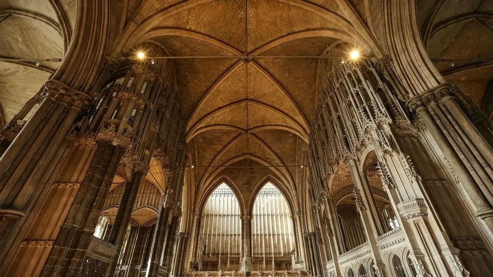 Interior de uma catedral gótica com altas abóbadas de nervuras e colunas imponentes.
