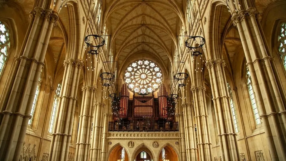 Interior de uma catedral gótica com uma grande rosácea acima do órgão central.