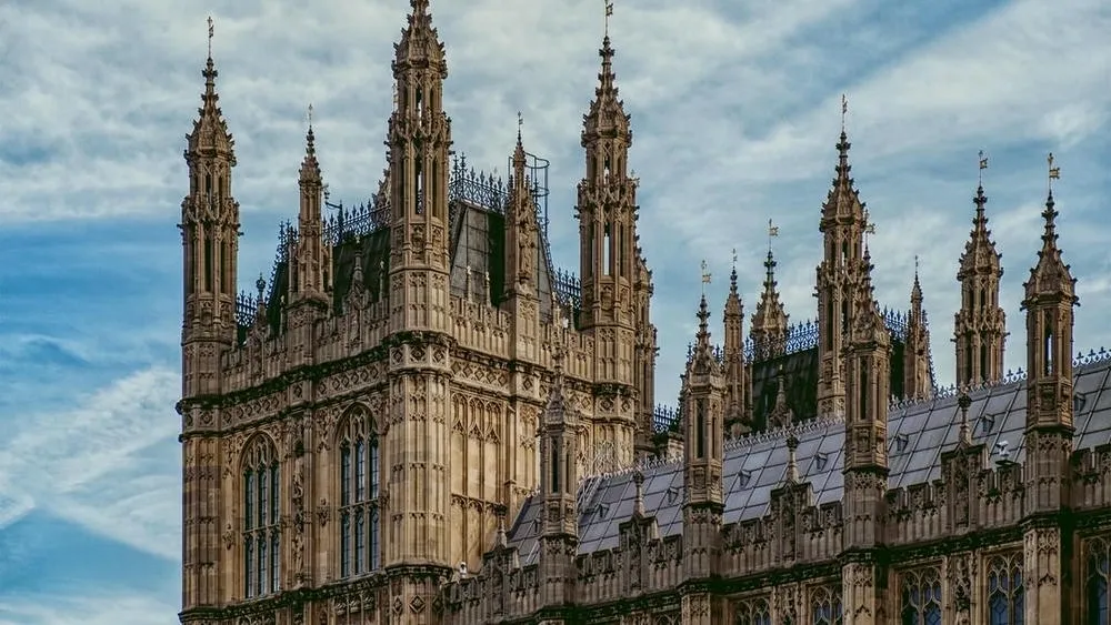 Vista de torres pontiagudas e detalhes ornamentados do Palácio de Westminster, um edifício neogótico.
