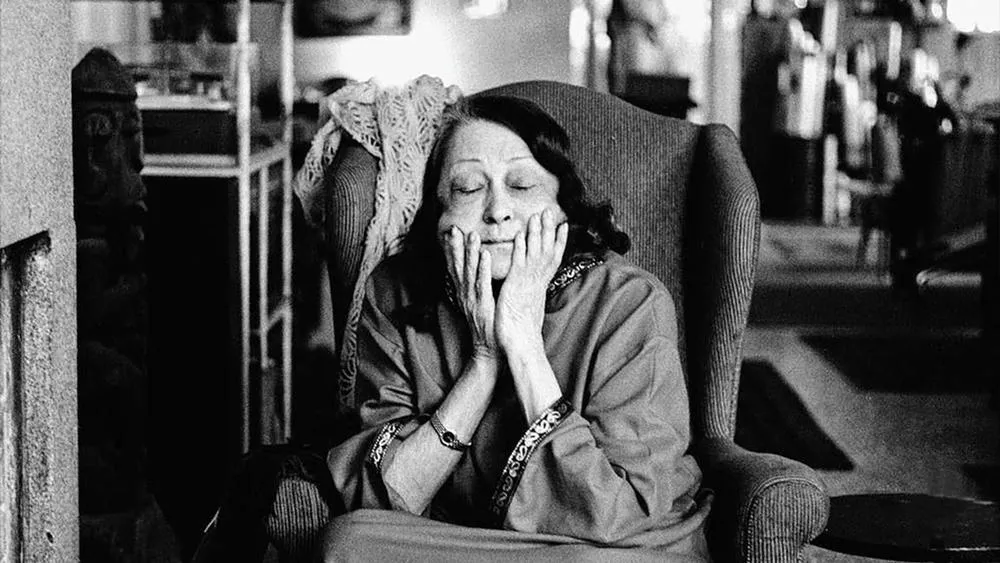 Lina Bo Bardi in a moment of work, wearing a hat, analyzing a project.