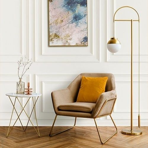 Ambiente interno com boiserie na parede, poltrona bege, mesa de apoio e luminária de chão, criando uma atmosfera elegante e convidativa.