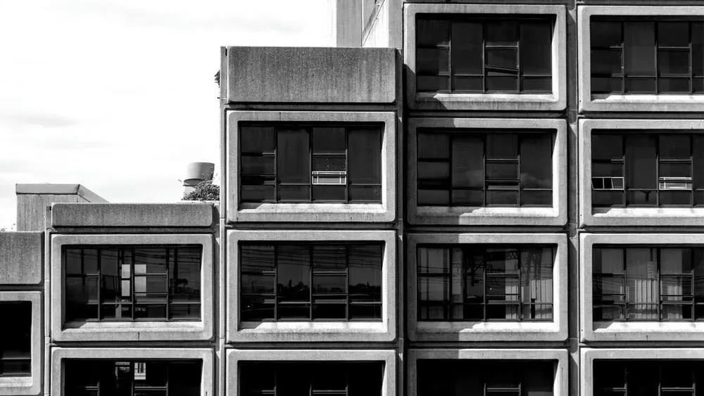 Close-up of a brutalist building facade, showing the repetition of concrete modules with square windows.