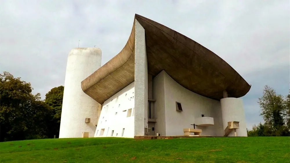 Capela Notre Dame du Haut em Ronchamp, uma obra religiosa de Le Corbusier com formas orgânicas e iluminação dramática.