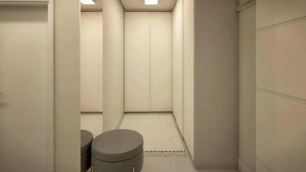 Closet fechado com portas claras e um pufe cinza no centro, proporcionando um ambiente limpo e discreto.