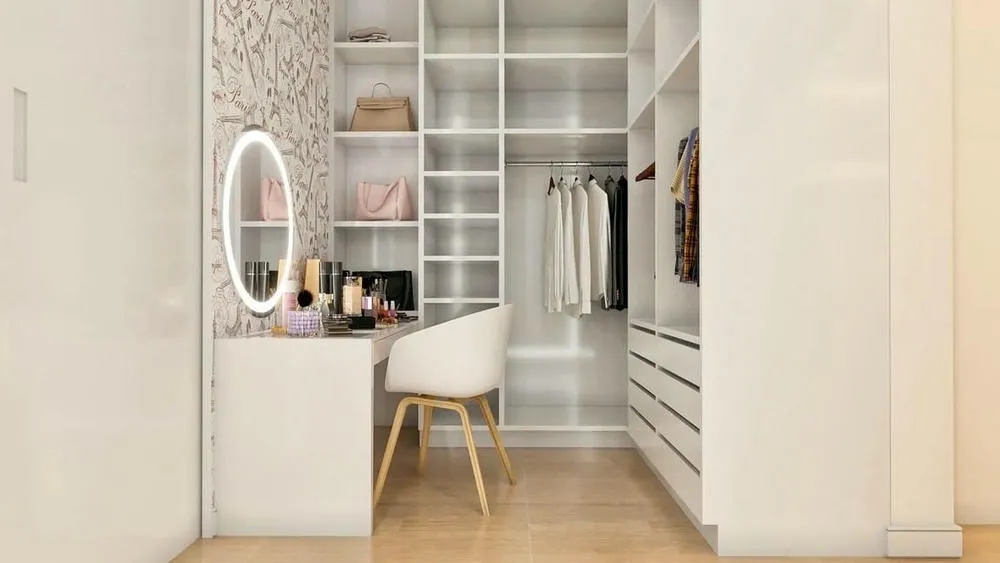 White vanity with illuminated mirror and makeup products, integrated into an open-shelf closet.