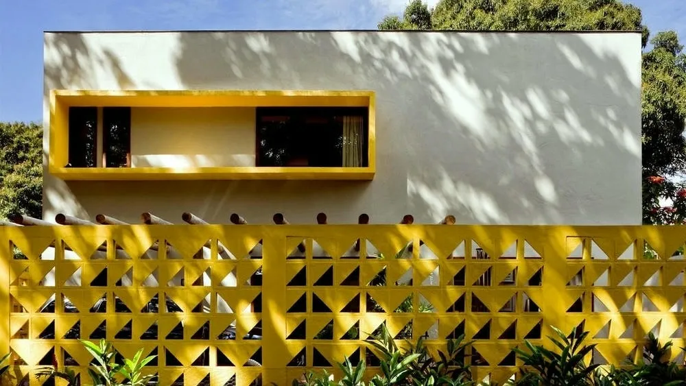 Wall with yellow cobogós in a geometric pattern, creating a striking and functional visual effect in architecture, offering ventilation and shading.