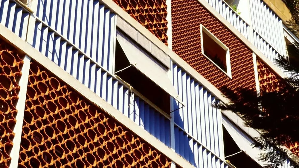 Building with a ceramic cobogó facade in earthy tones and white brises, creating a unique and functional visual pattern in Brazilian architecture.