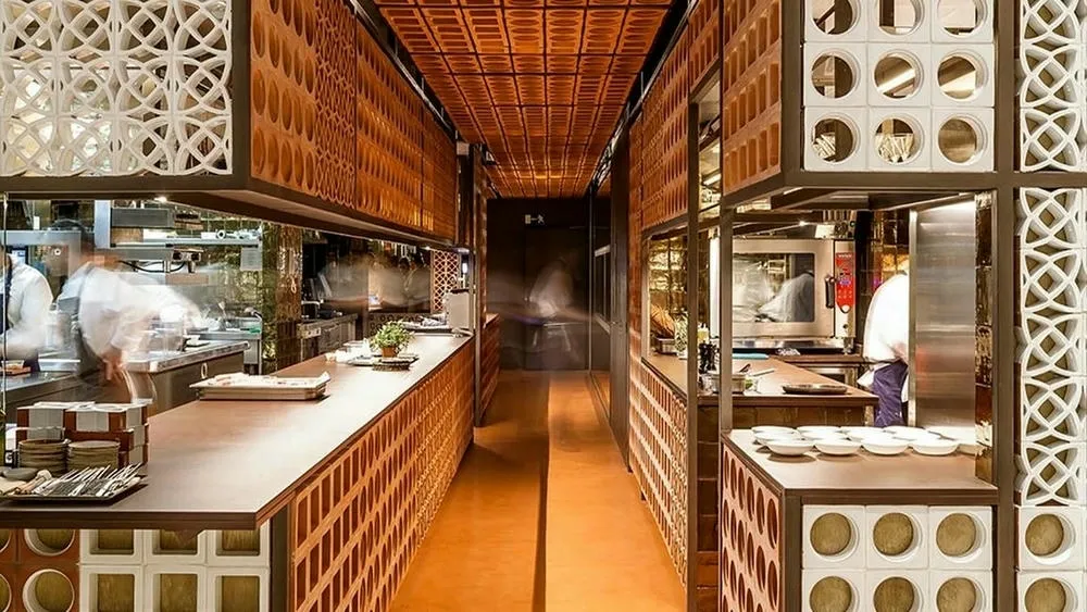 Cocina moderna con pared de cobogós en tonos tierra y detalles en blanco, demostrando la aplicación de los cobogós en el diseño de interiores para crear texturas y divisiones sutiles.