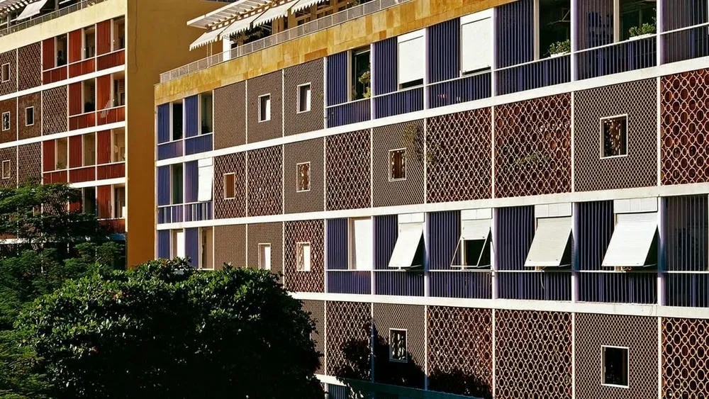 Fachada de edificio con diferentes tipos de cobogós, incluyendo cerámica en tonos tierra y elementos en azul, evidenciando la variedad de diseños y materiales de los cobogós.