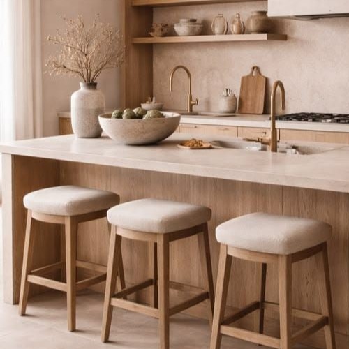 Cozinha em estilo Japandi com bancada de pedra clara, armários de madeira clara e banquetas estofadas em tom neutro, realçando o minimalismo e o aconchego.