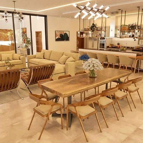 Uma sala de estar, jantar e cozinha integradas em um conceito aberto, com sofás, mesa de jantar e ilha de cozinha, valorizando a amplitude do espaço.