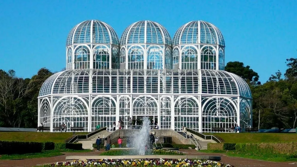 Jardín Botánico de Curitiba, con el invernadero de vidrio en estilo Art Nouveau y un espejo de agua con fuente.