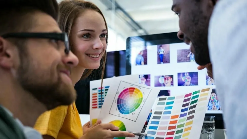 Uma pessoa praticando a mistura de cores com tintas e um círculo cromático ao lado, incentivando a experimentação.