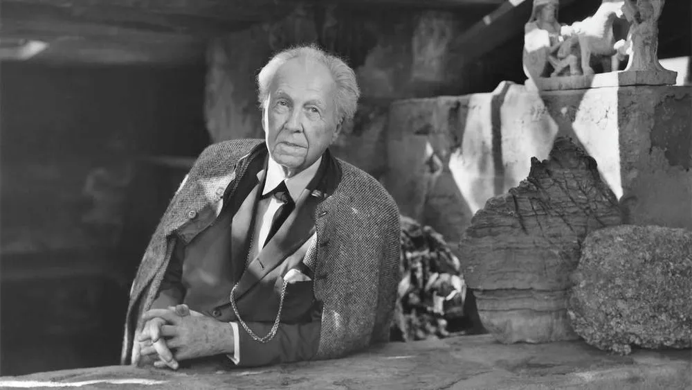 Retrato em preto e branco de Frank Lloyd Wright, arquiteto famoso, em pose pensativa.