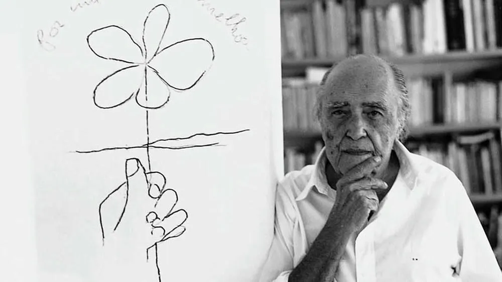 Oscar Niemeyer em um momento de reflexão, com uma de suas frases célebres sobre a beleza das curvas na arquitetura.
