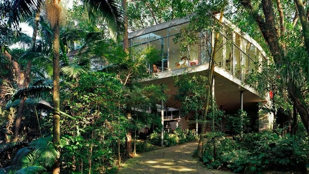 View of the Glass House, with its transparent structure and integration with the surrounding vegetation, amidst nature.