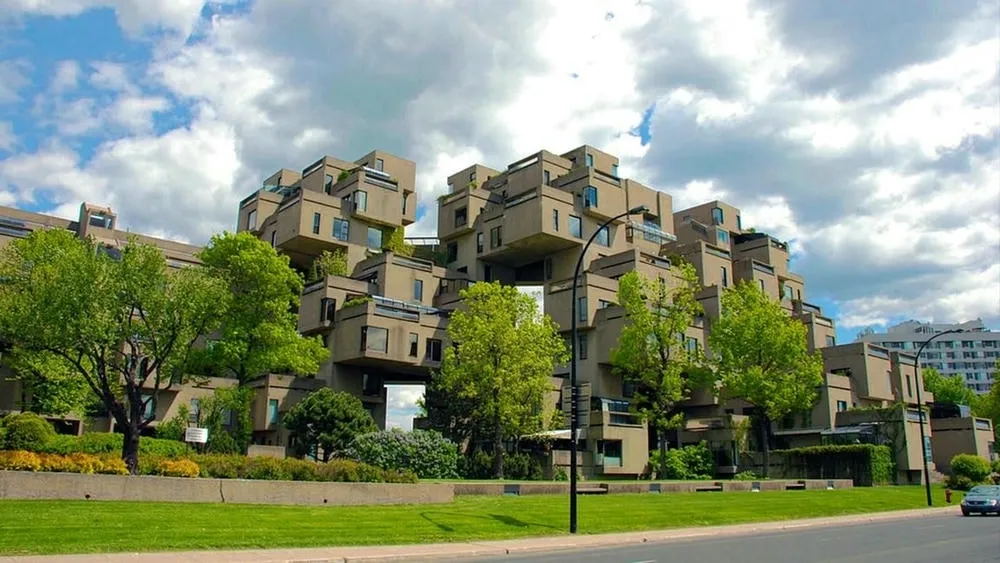 Exterior view of Habitat 67 in Montreal, Canada, with its prefabricated concrete blocks and vegetation, representing brutalist and residential architecture.
